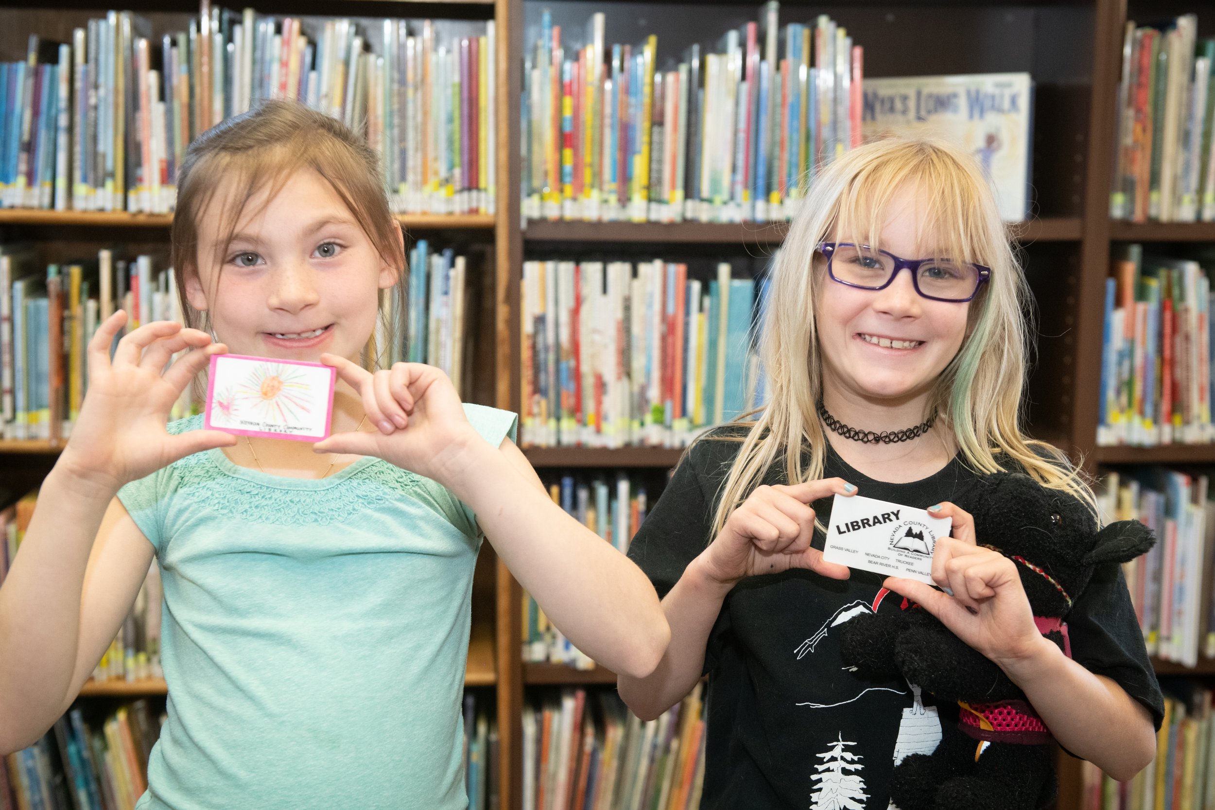 girls holding up their library cards