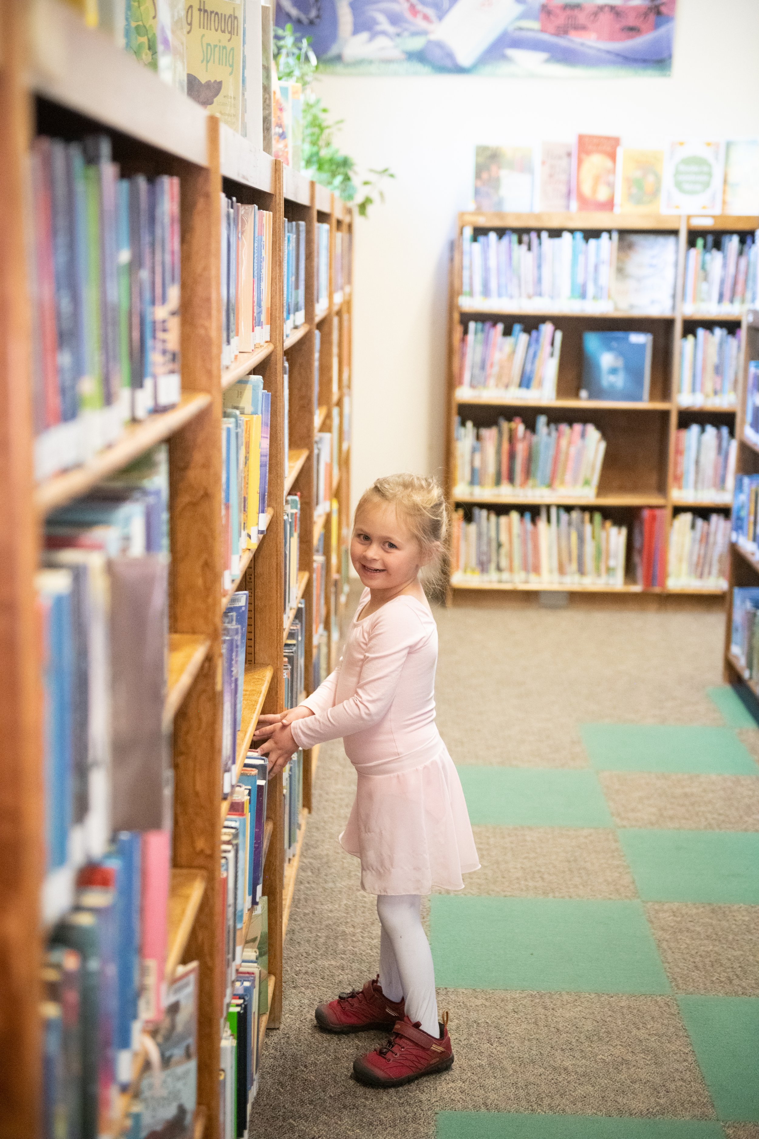 girl picking out book at the library