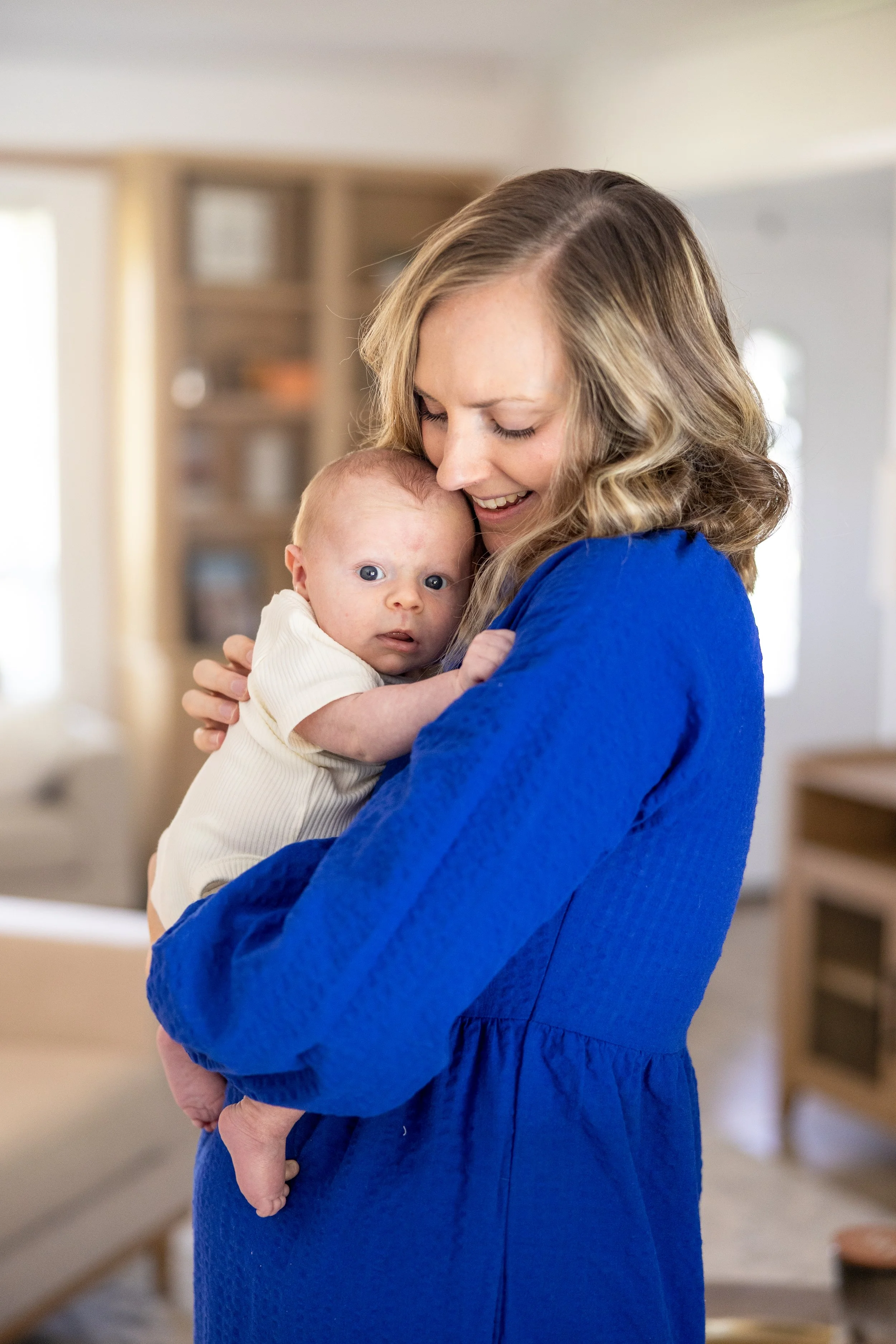 College Station maternity and newborn photography by Mandy Laine Photo: a mother cradles her newborn in a cozy nursery, captured in natural light for tender, timeless motherhood moments.