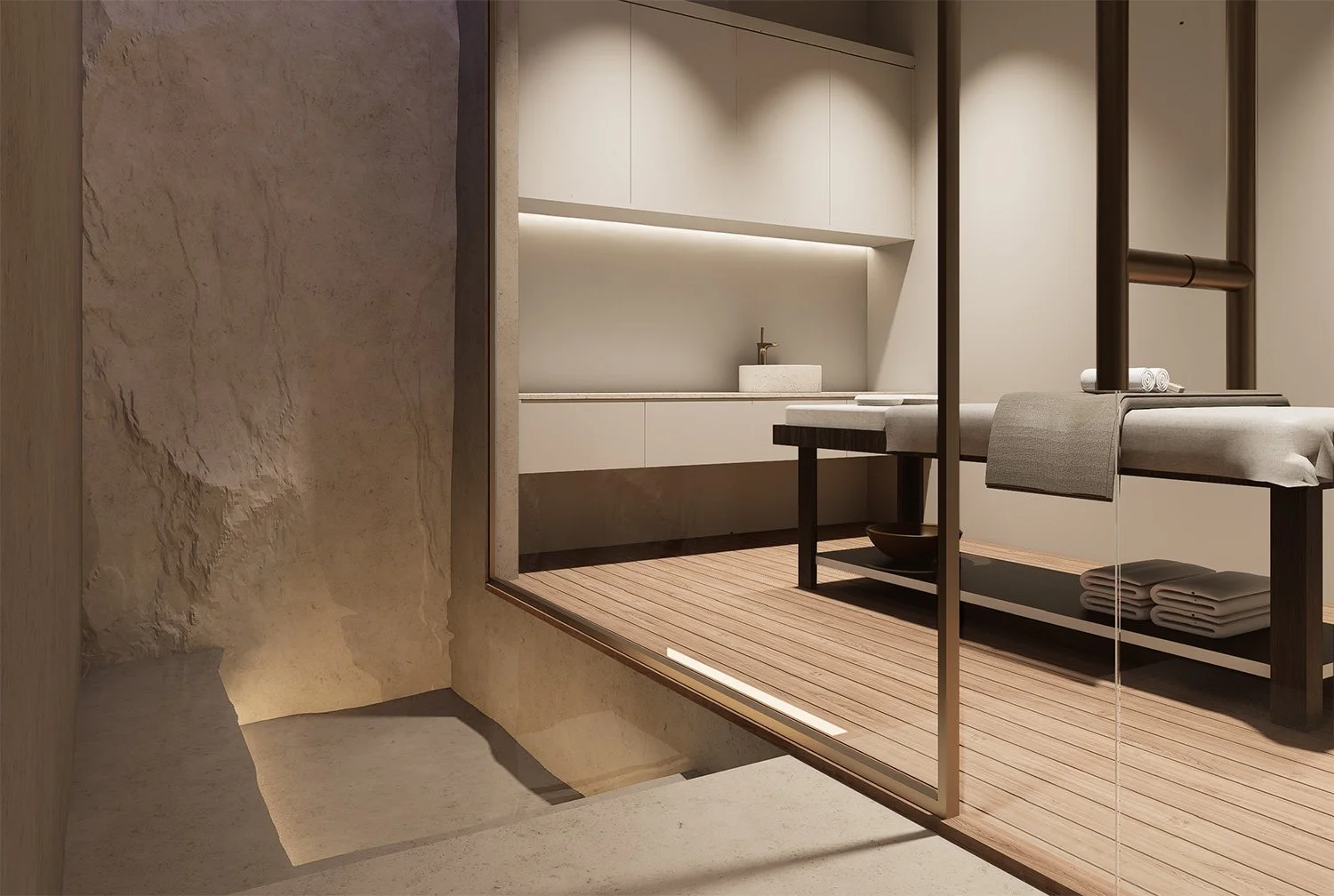 Spa or massage treatment room with a wooden table, rolled towels, a stone basin, and minimalist decor, viewed through a glass partition.