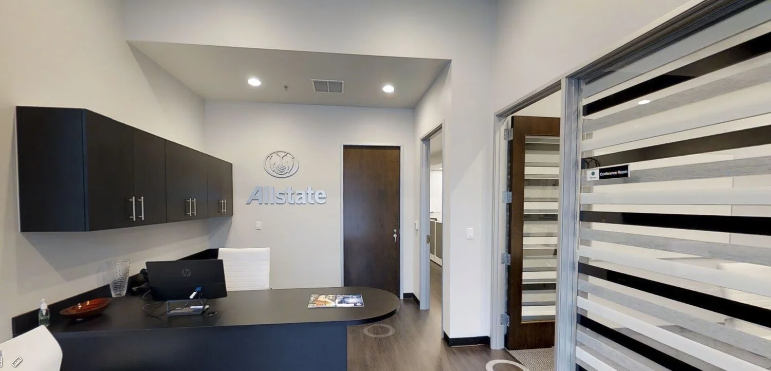 Allstate insurance office reception area with black cabinets, a desk with computer and white chair, and a conference room door on the right with frosted glass panels