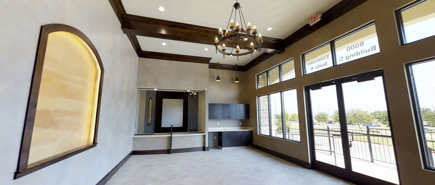 Empty restaurant or cafe with large windows, chandelier, and a small built-in counter area.