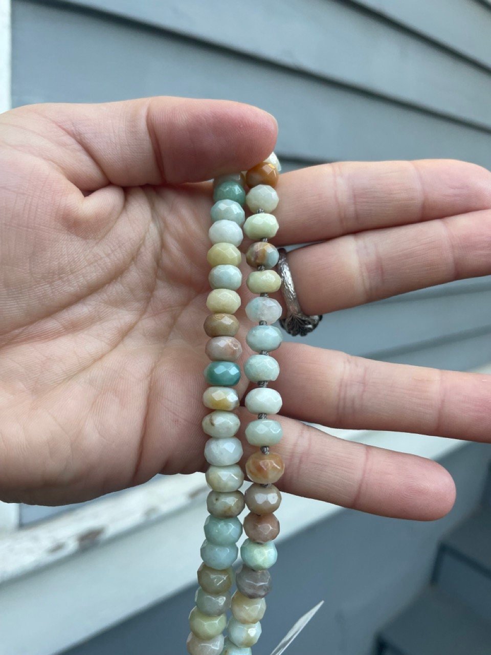 hand holding necklace made of semiprecious gemstone mixed amazonite hand knotted with silk thread