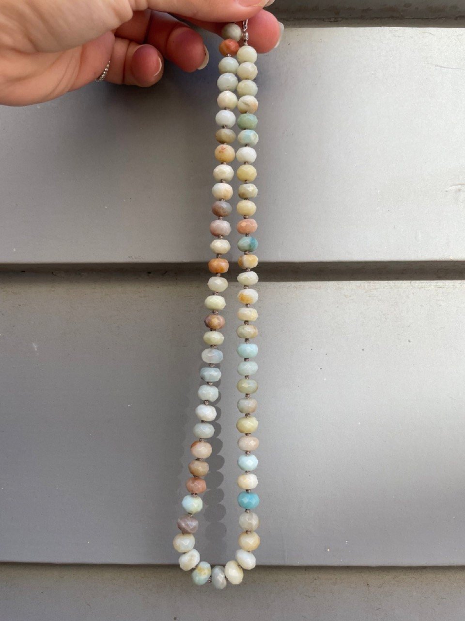 hand holding necklace made of semiprecious gemstone mixed amazonite hand knotted with silk thread