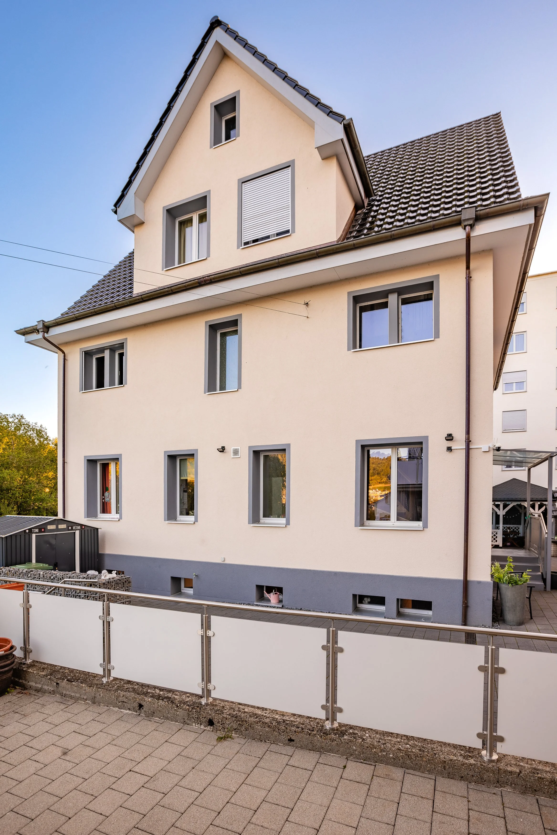 Mehrstöckiges Haus mit beige Fassade, grauen Fensterrahmen, Satteldach und kleiner Terrasse. Haus in Neuhausen kaufen bei FREITAG IMMO: www.freitagimmo.ch