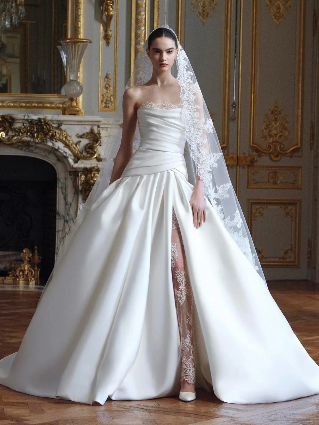 New Arrival from @eliesaabbridal. An elegant strapless silhouette, sculpted corsetry and a drop waist meet fluid draping, a daring slit, delicate lace detailing &amp; crafted in luminous mikado. Book your private appointment now.