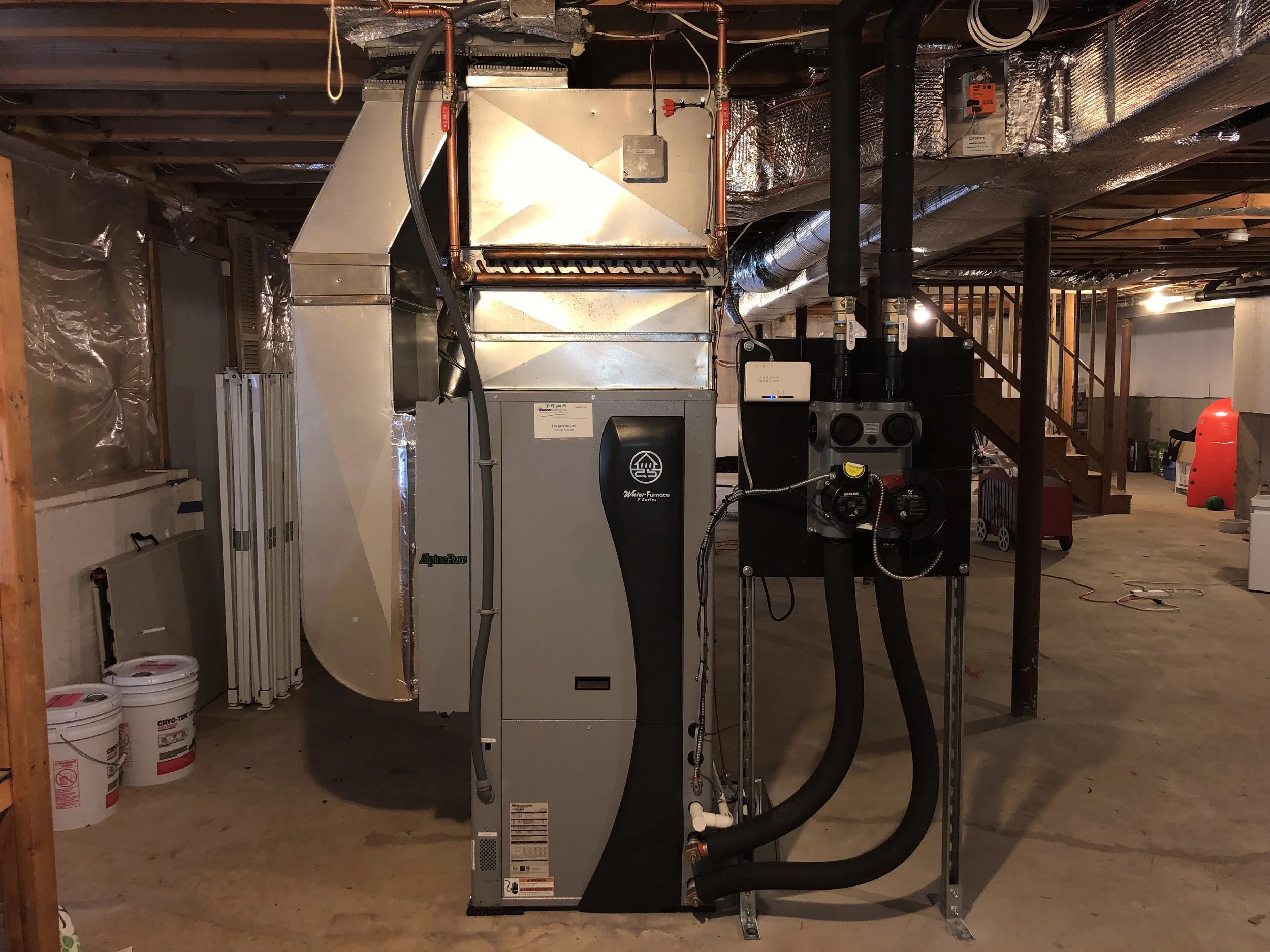 Illustration of a house with geothermal heating system, showing underground geothermal pipes in red and blue loops.