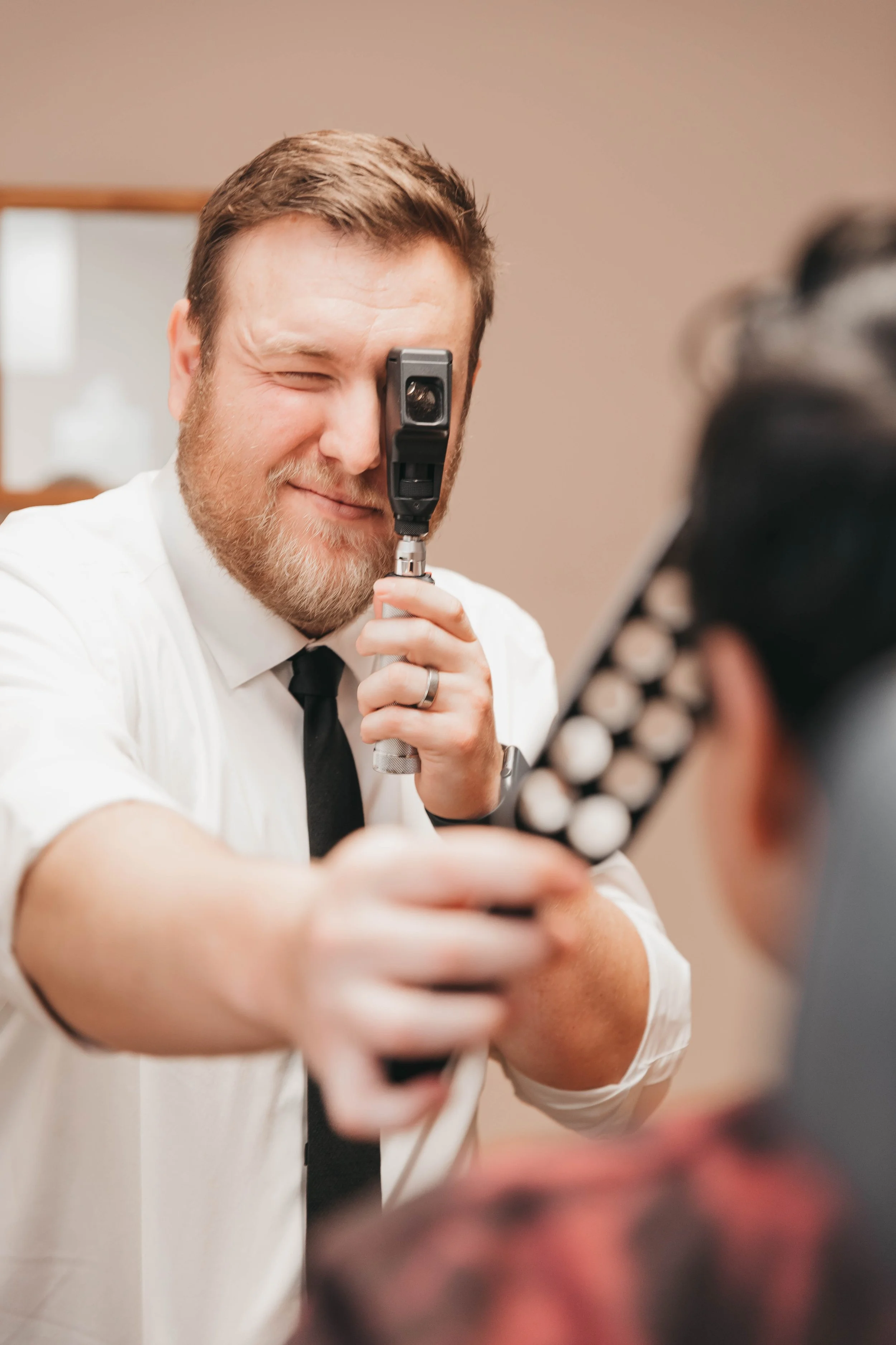 Eye exam in optometry clinic showing doctor using handheld measuring device for vision assessment and patient evaluation