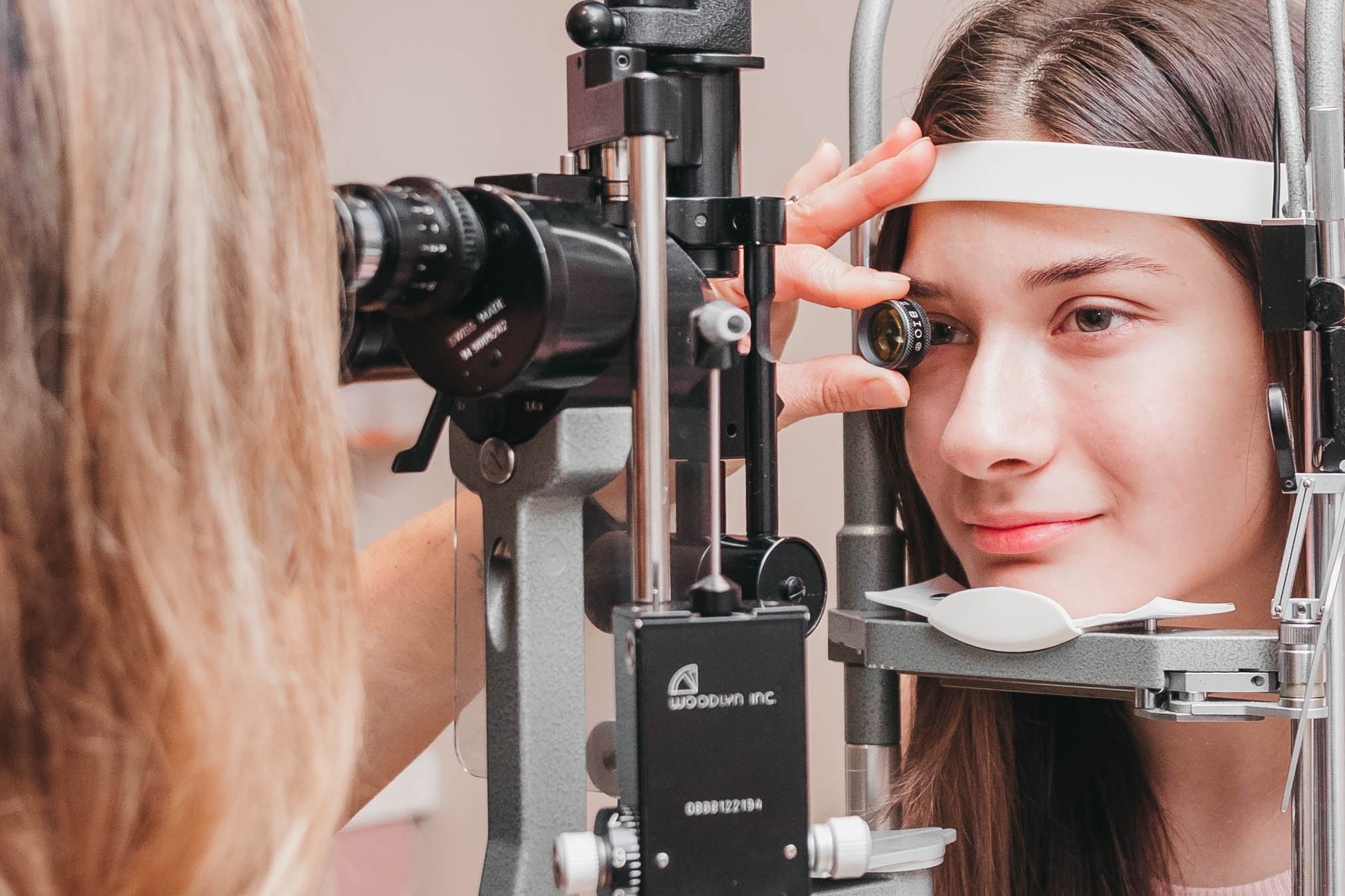 Child undergoing slit lamp eye examination with optometrist in clinical setting