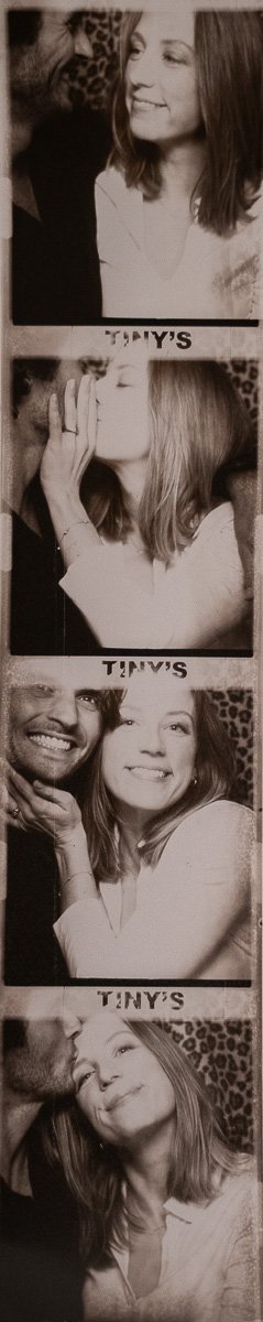 A photo strip showing four black-and-white pictures of a woman with light-colored hair and a man with dark hair. The woman is smiling in the first picture, pretend kissing in the second, smiling again in the third with the man, and being kissed on the cheek by the man in the fourth.