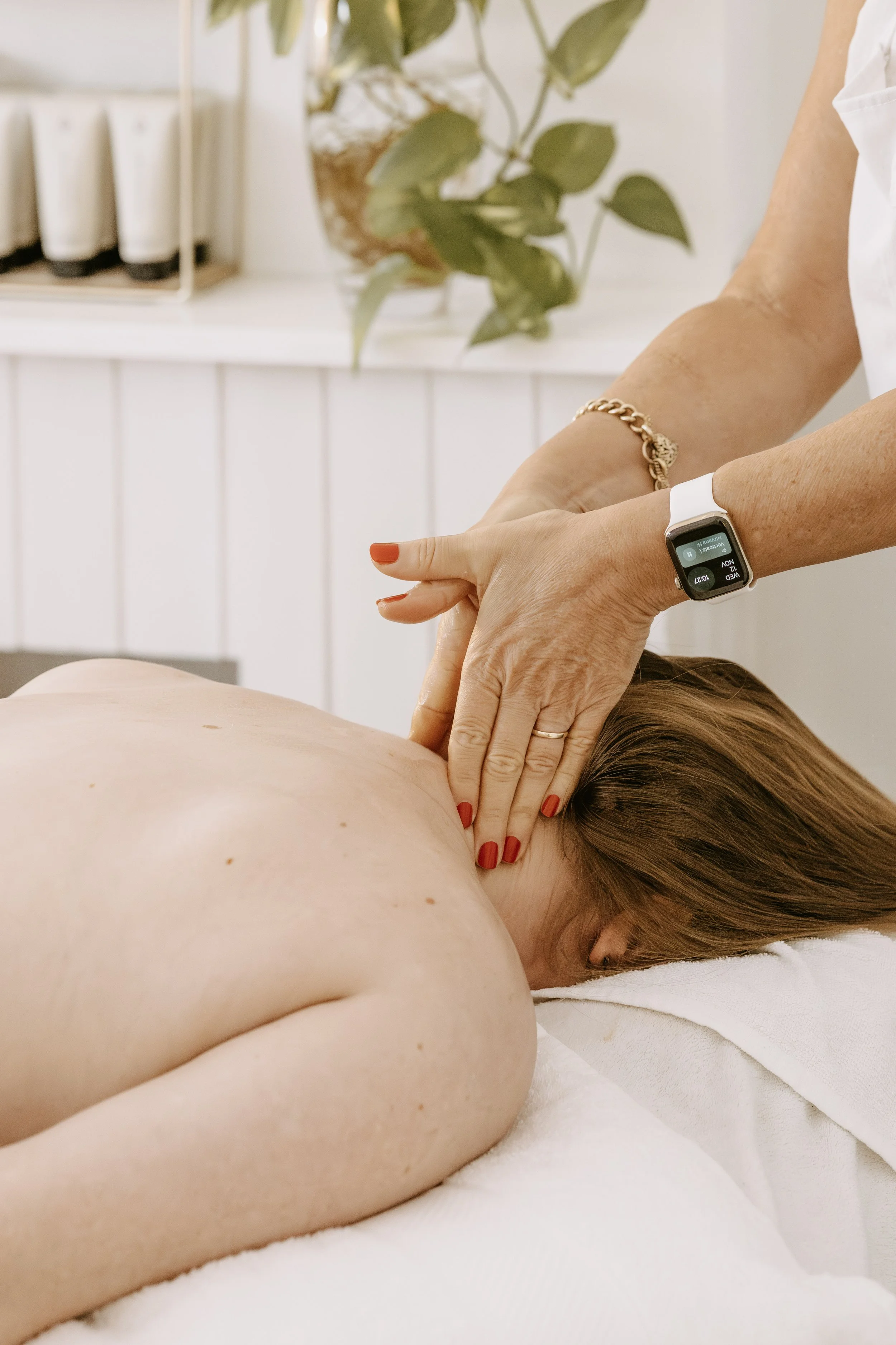 Woman receiving a massage with candles and flowers in a spa setting.