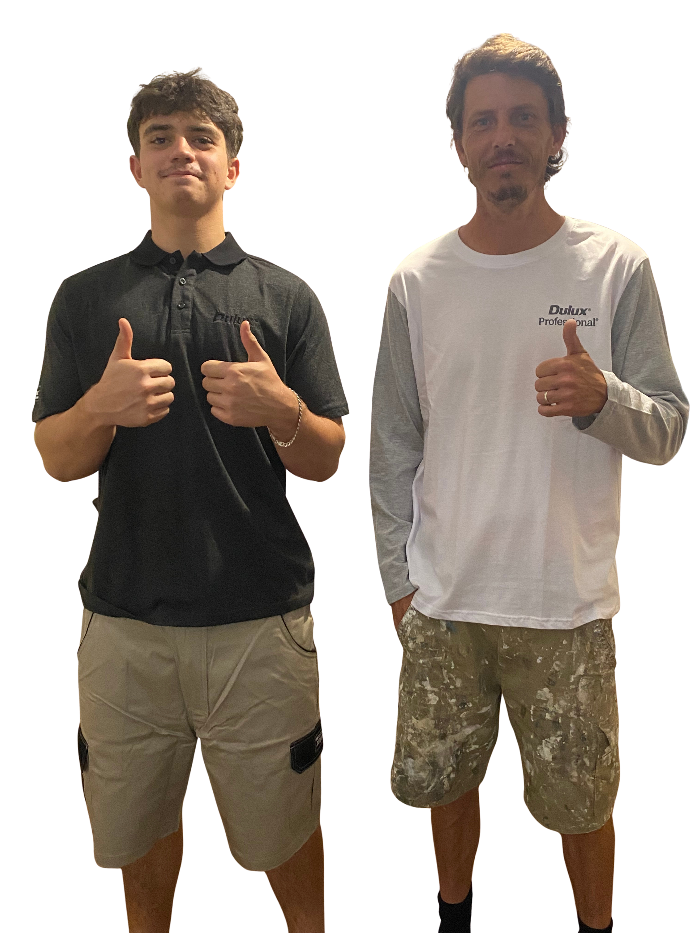 Two young men standing side by side, each giving a thumbs-up gesture, one wearing a black polo shirt and beige cargo shorts, and the other in a white long-sleeve shirt with camouflage shorts.