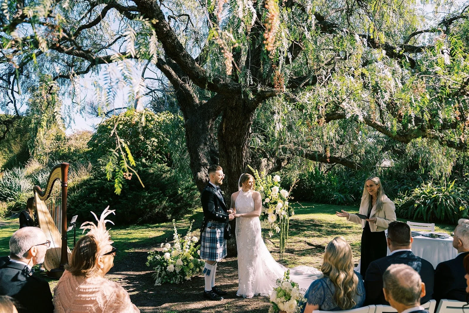 Sarah & Andrew under the trees at Como House with live harp - simple, heartfelt. Photo by Redbook Studios.