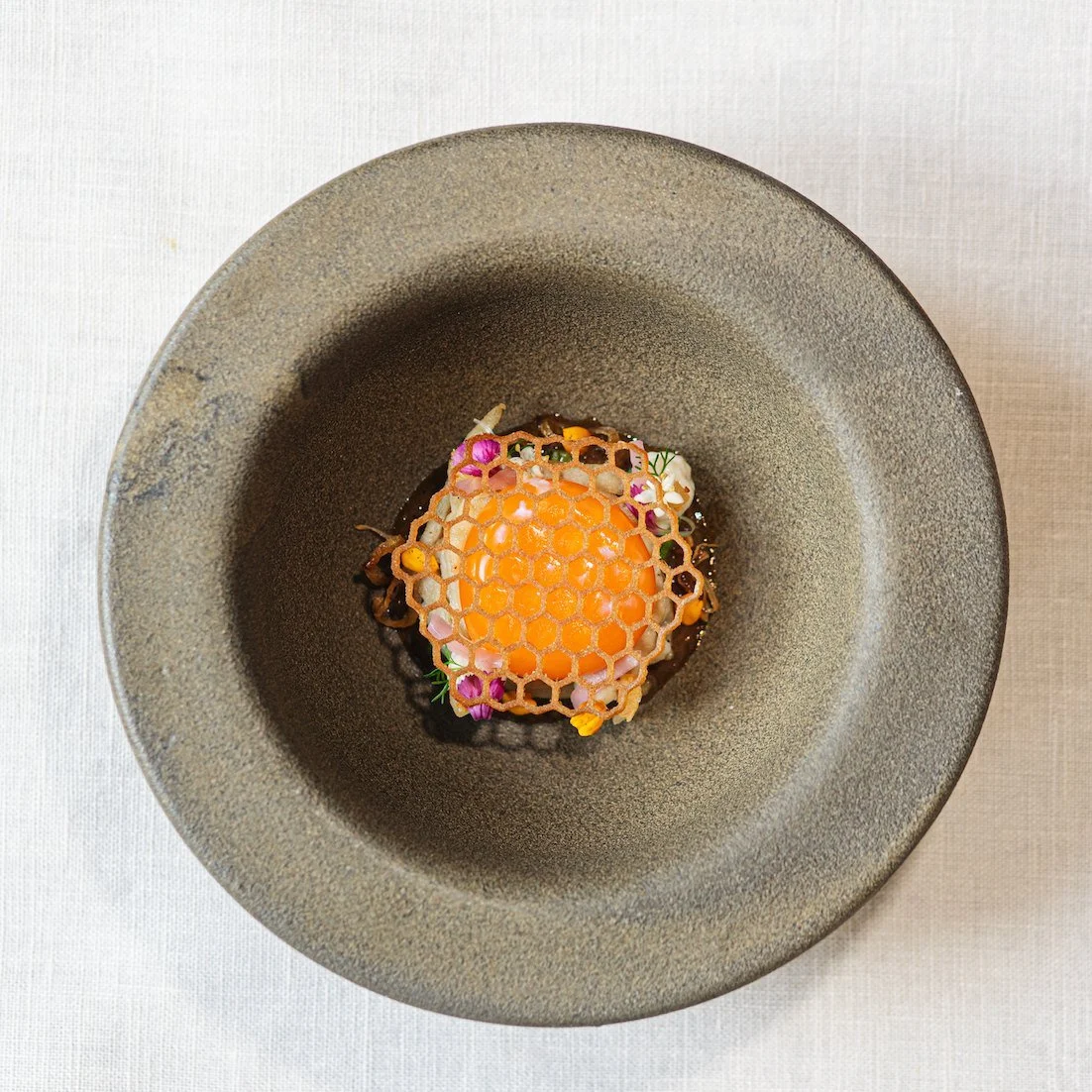Overhead view of a honeycomb tuile course in a stoneware bowl at Royd