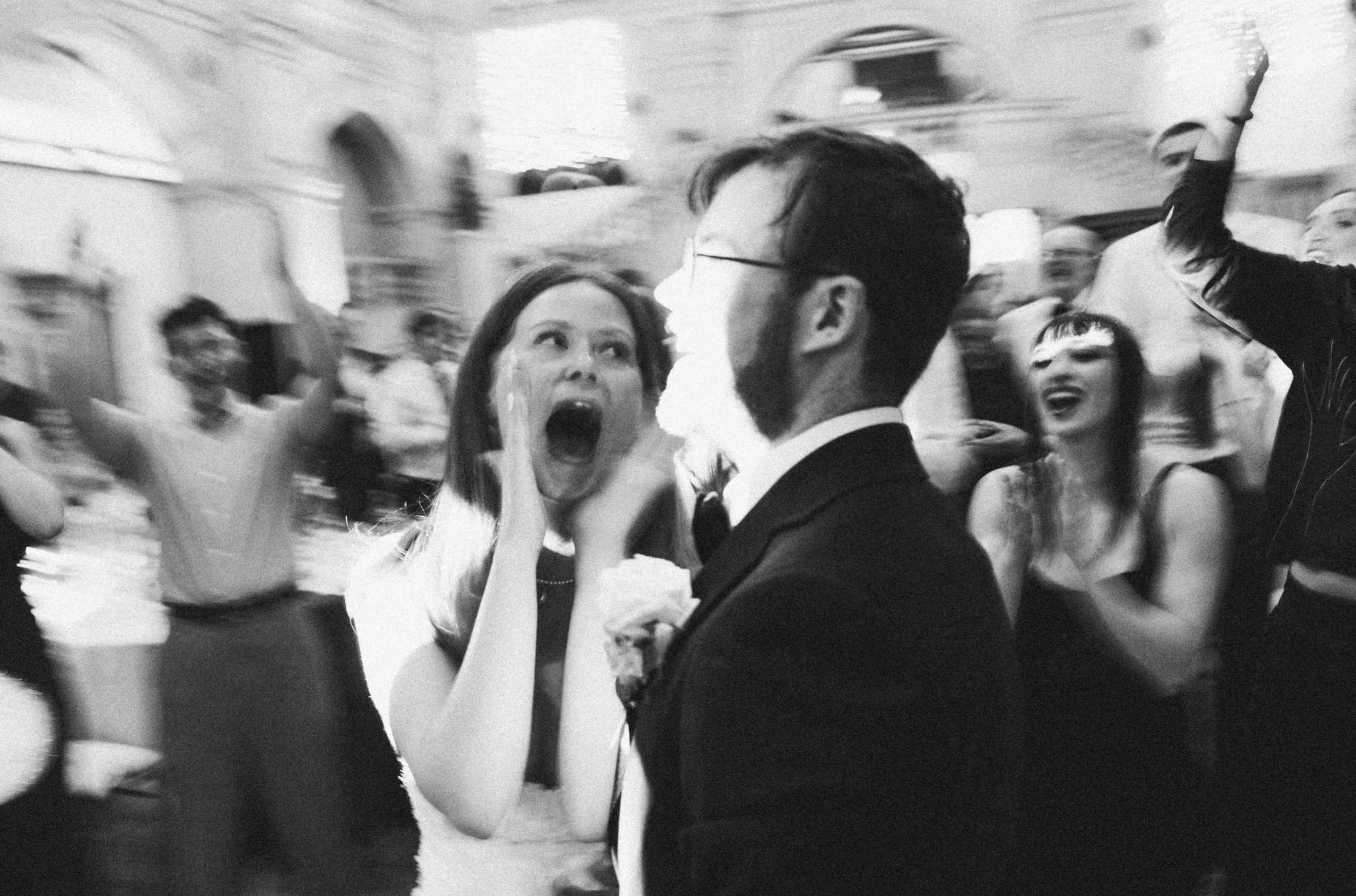 black and white photo of a bride and groom on a dancefloor at their wedding, the bride is pulling a scream style face in excitement at the groom at Bristol Museum