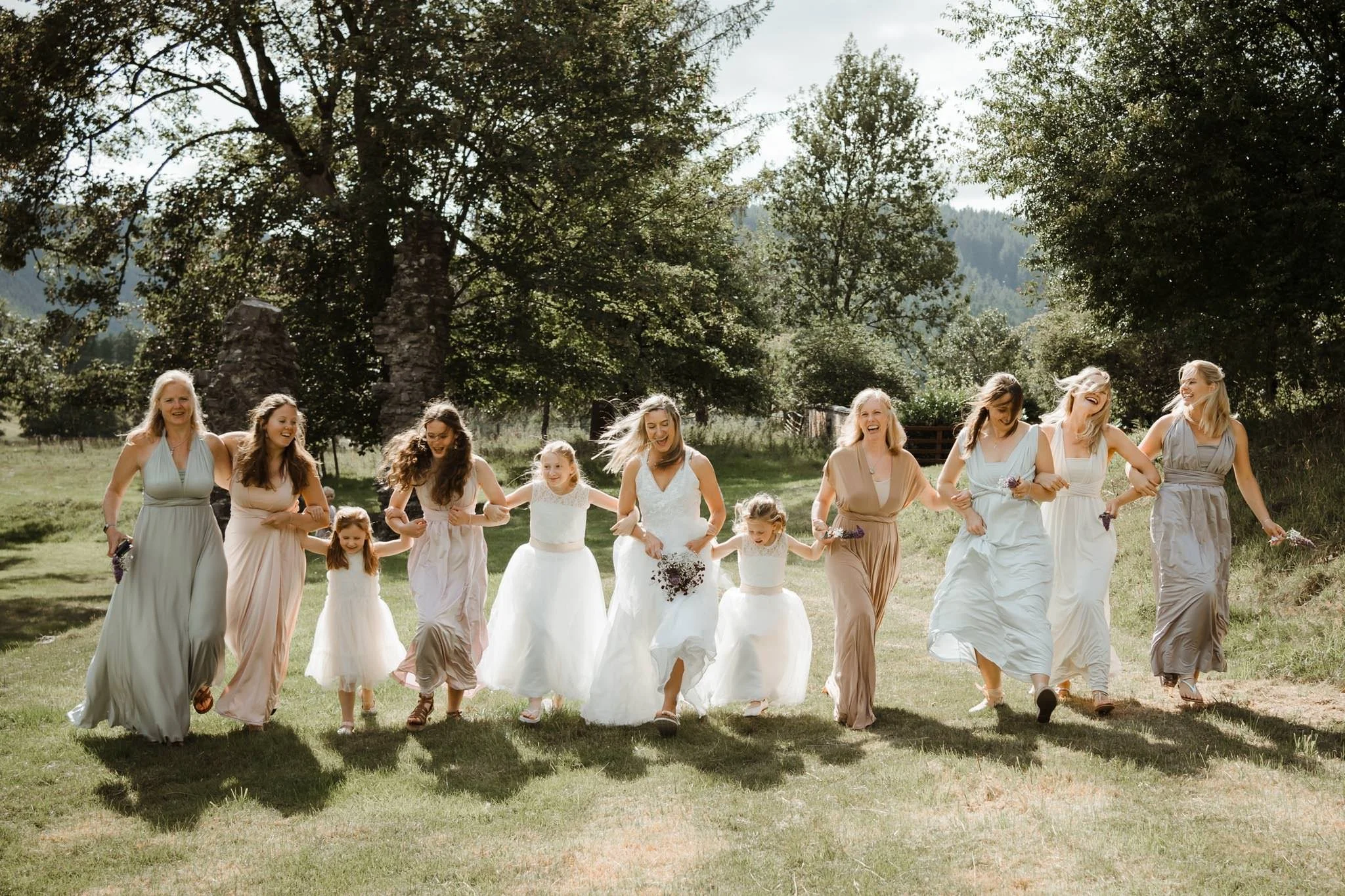 Bridesmaids running and having fun at a summer marquee wedding in Wales by Bristol wedding photographer