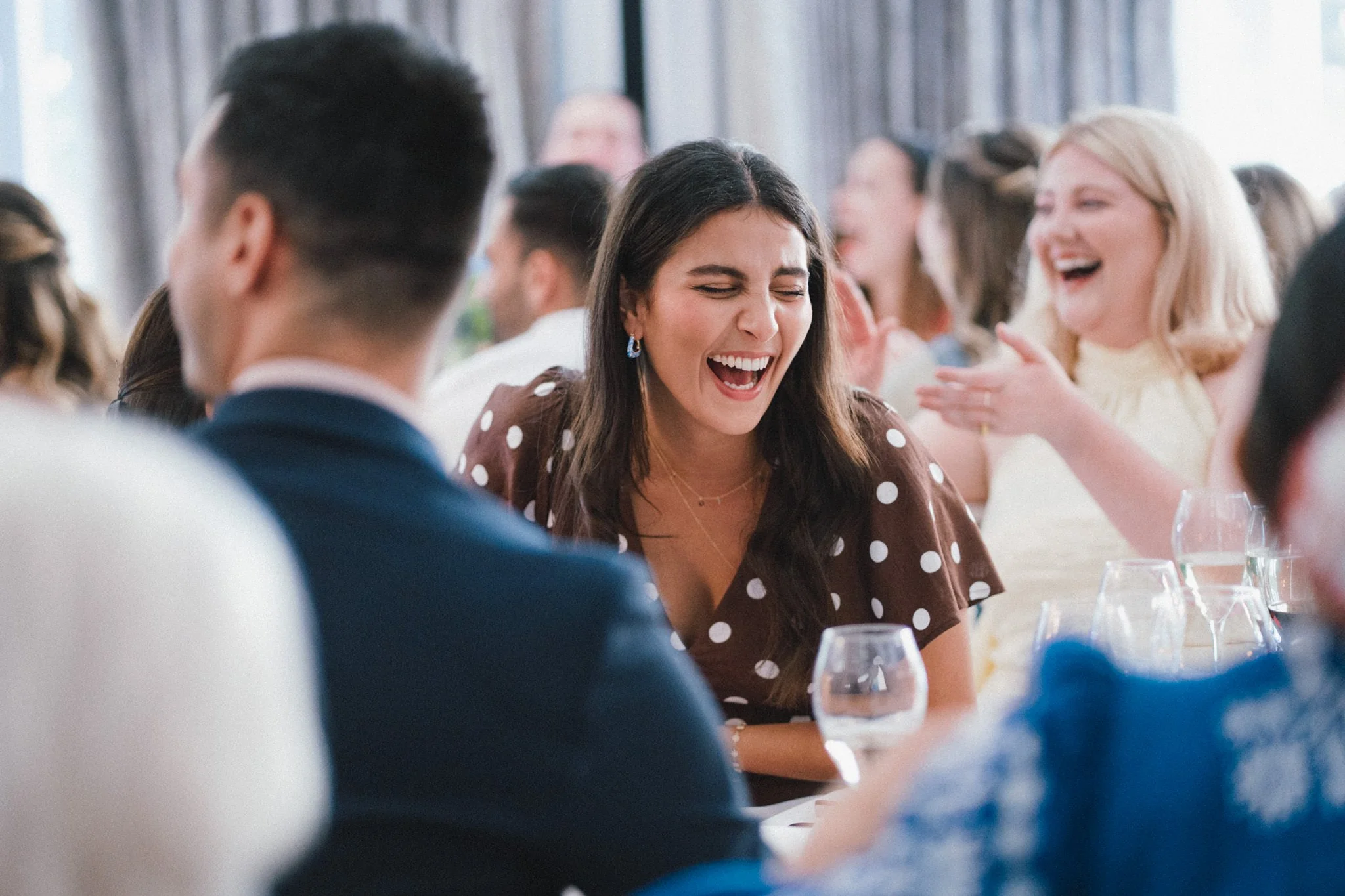 wedding photography of a female guest laughing during speeches