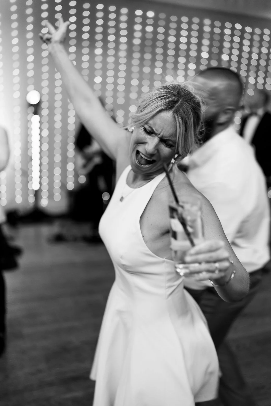 Guest dancing with arm raised, black and white wedding photography