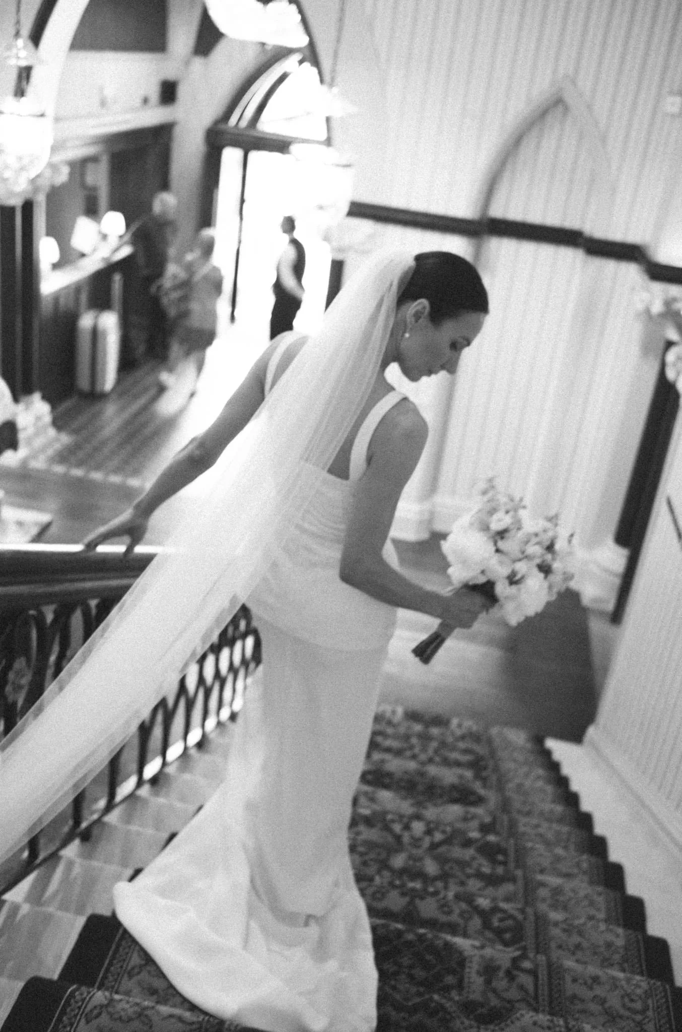 A bride descends the stairs at the Randolph Hotel in Oxford in black and white