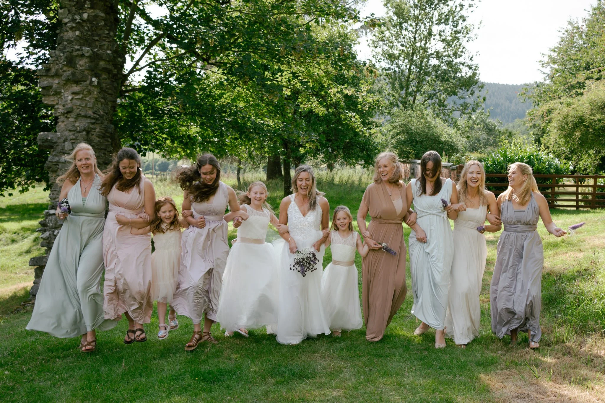 Bride and bridesmaids running toward the camera having fun and laughing