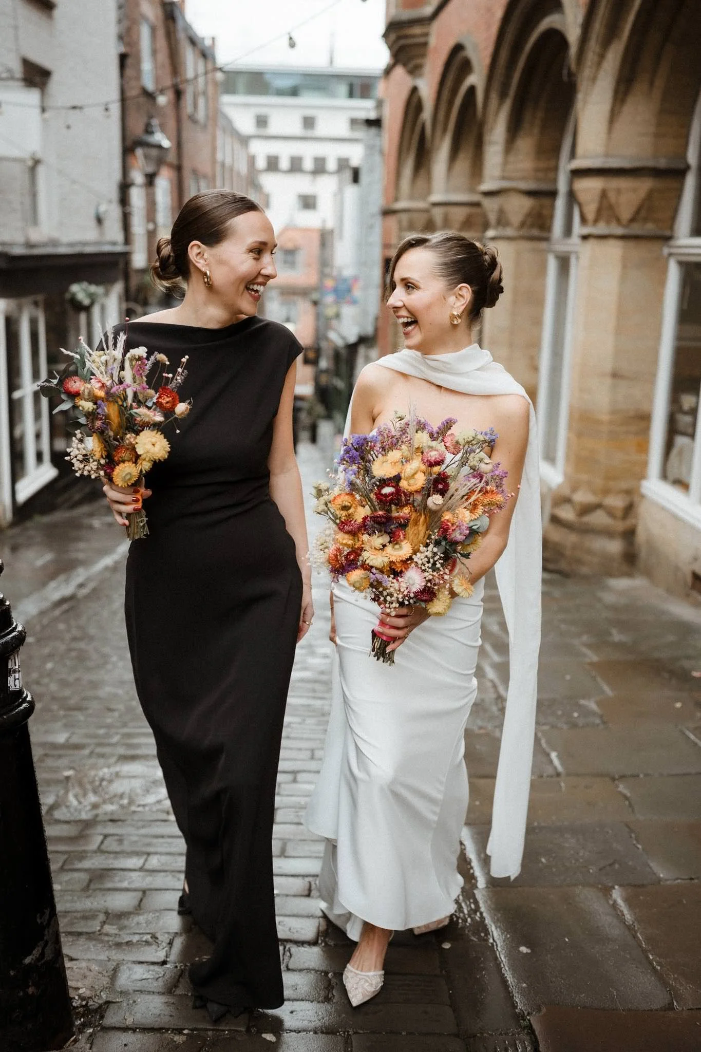 Photograph of stylish bride walking up Christmas Steps in Bristol with beautiful winter flowers in the rain