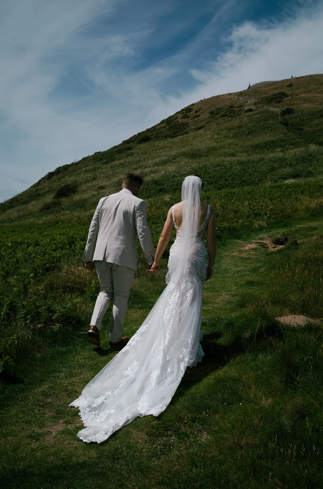 Bride and groom climbing a hill at Mwnt in Wales on their wedding day
