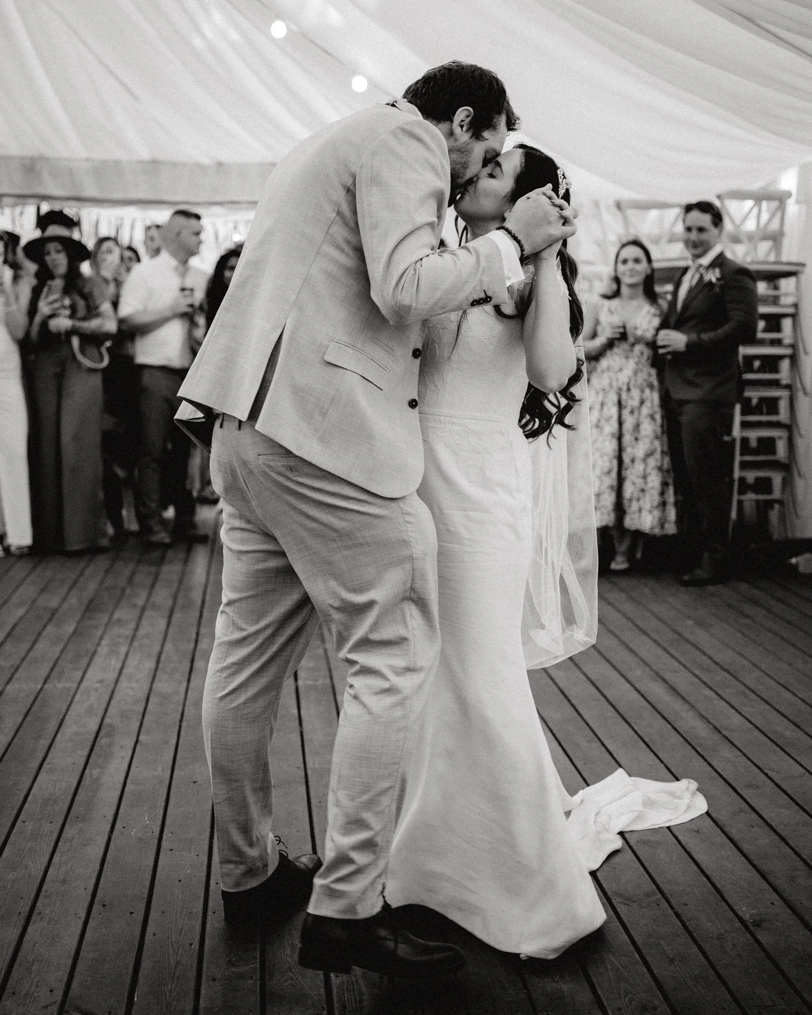 wedding photography of a really tall groom kissing a short bride on the dancefloor in black and white