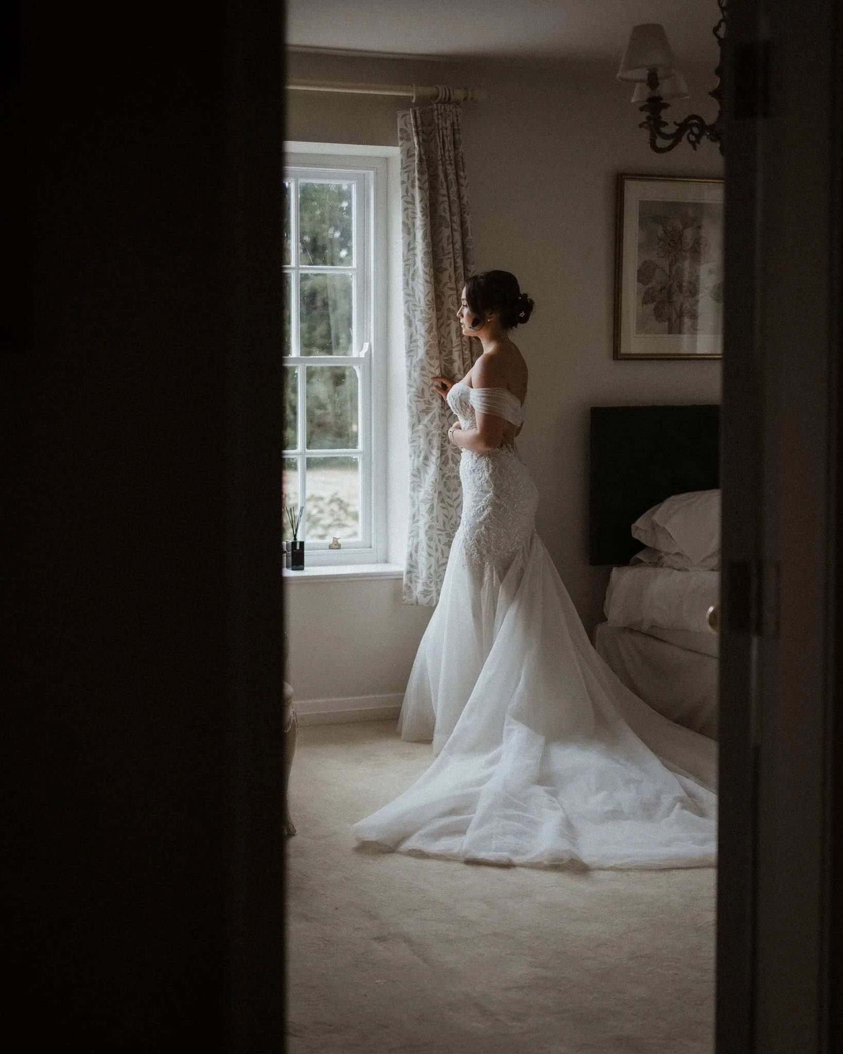 Bride looking out of the window at Birtsmorton Court on her wedding day 