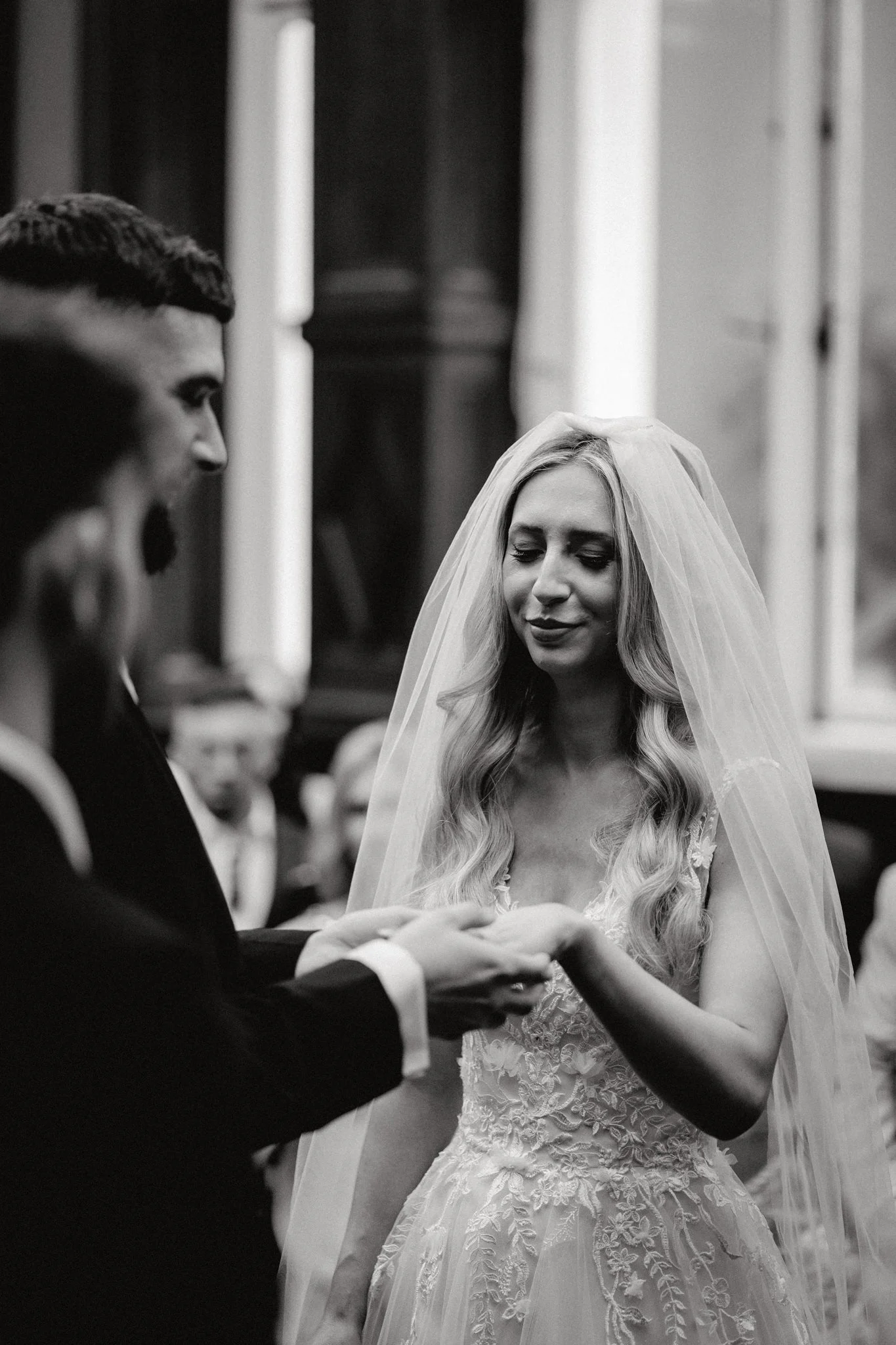 Groom puts a ring on his bride's finger during the ceremony at Bristol Registry Office in black and white