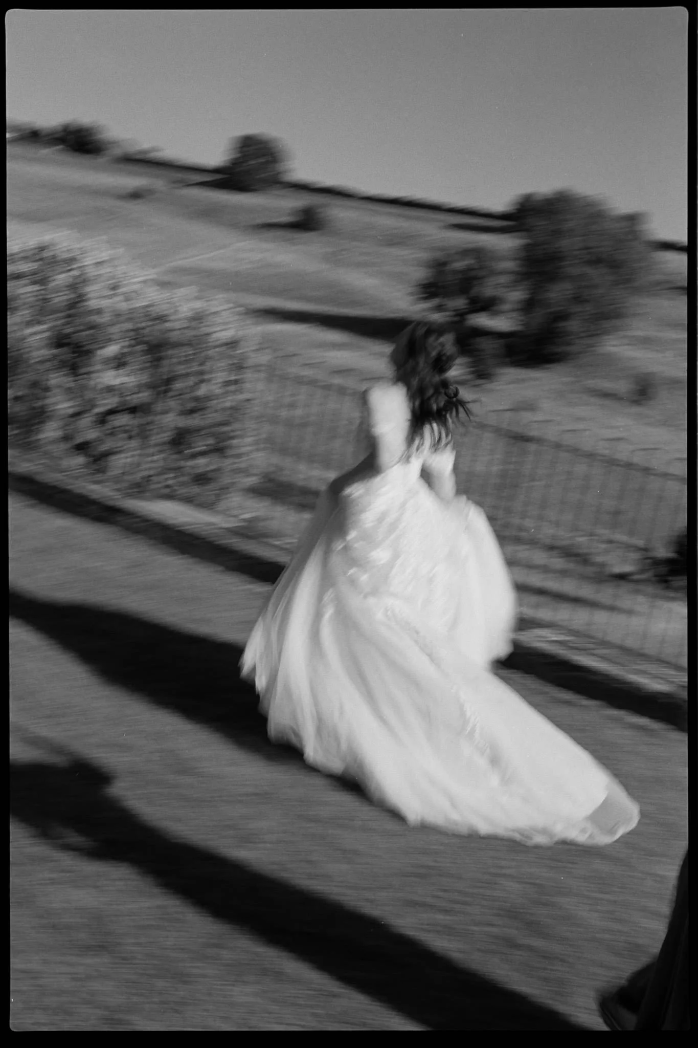 Bride runs away from the camera in black and white on film at Kingscote Barn