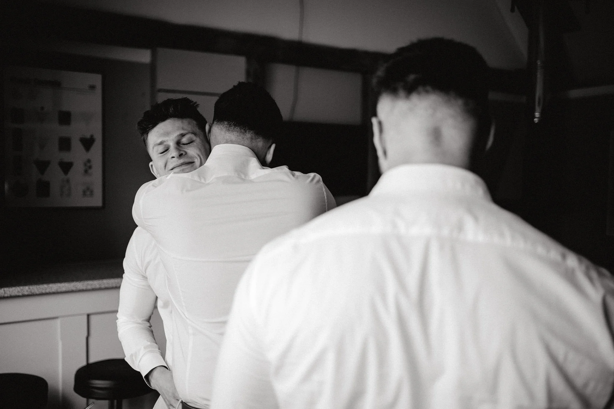wedding photography of groomsmen hugging in black and white 