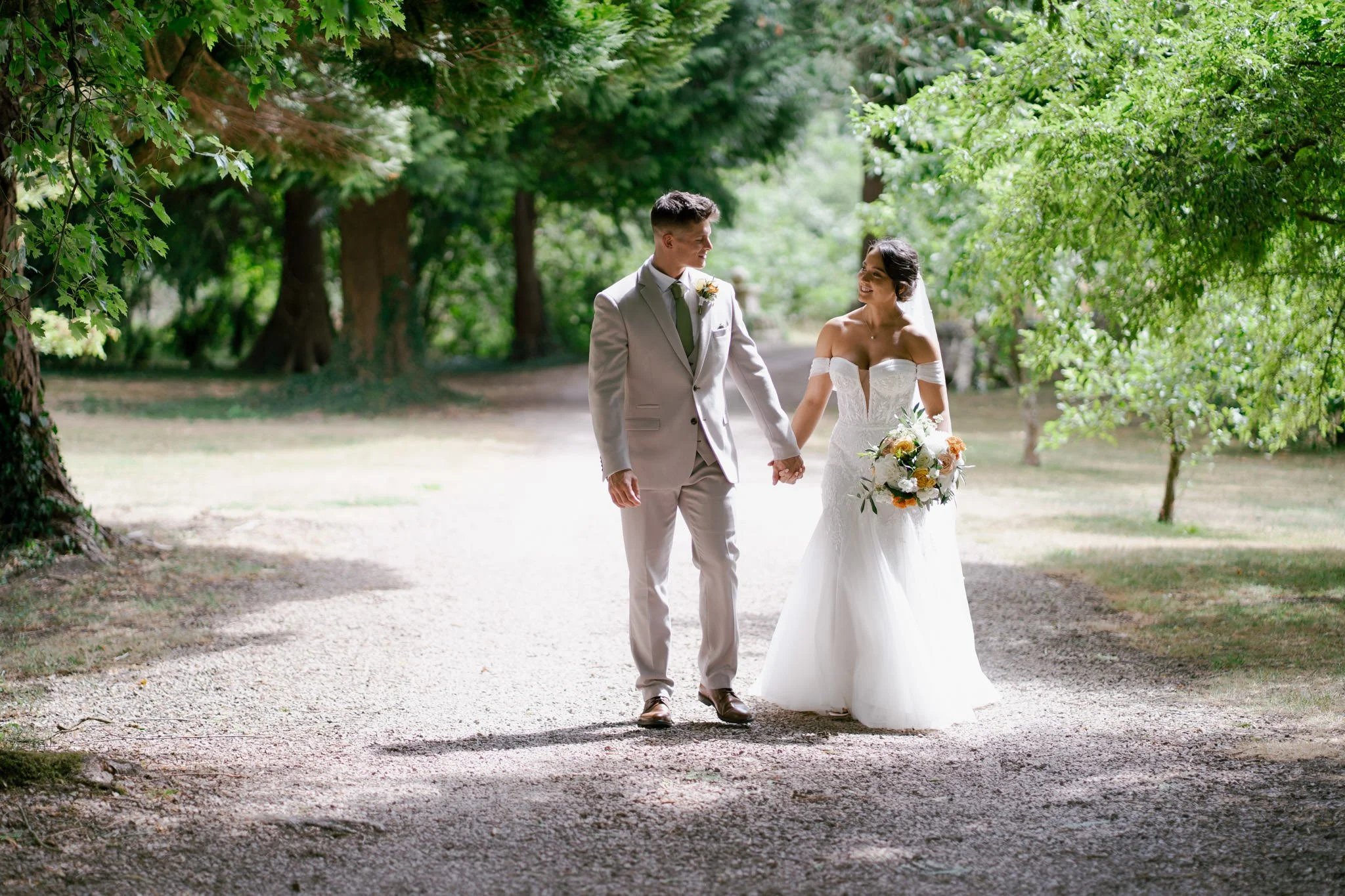 Bride and groom walking together under trees at Birtsmorton Court