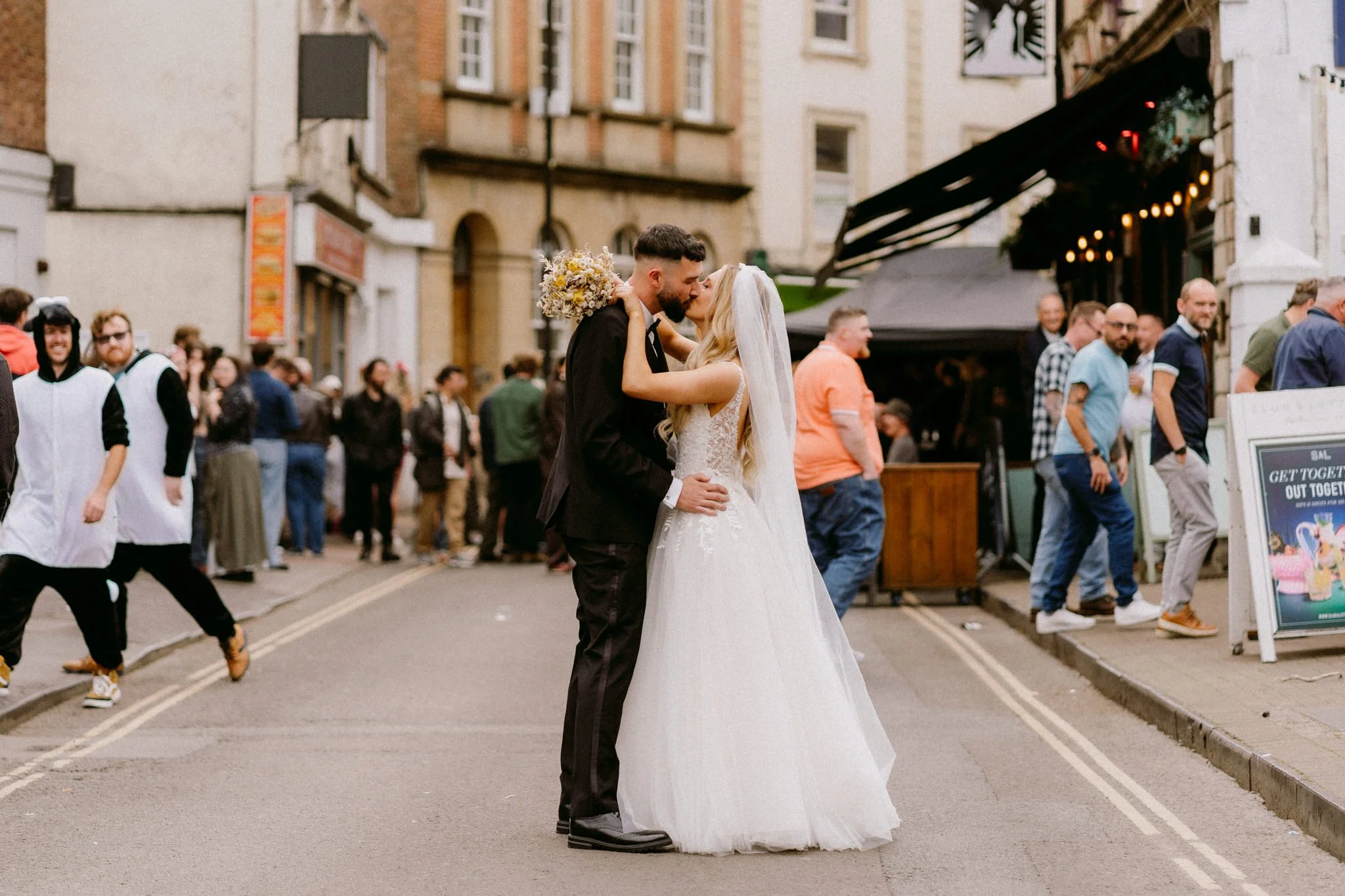 Bride and Groom kissing among lots of people near Radnor Rooms in Bristol