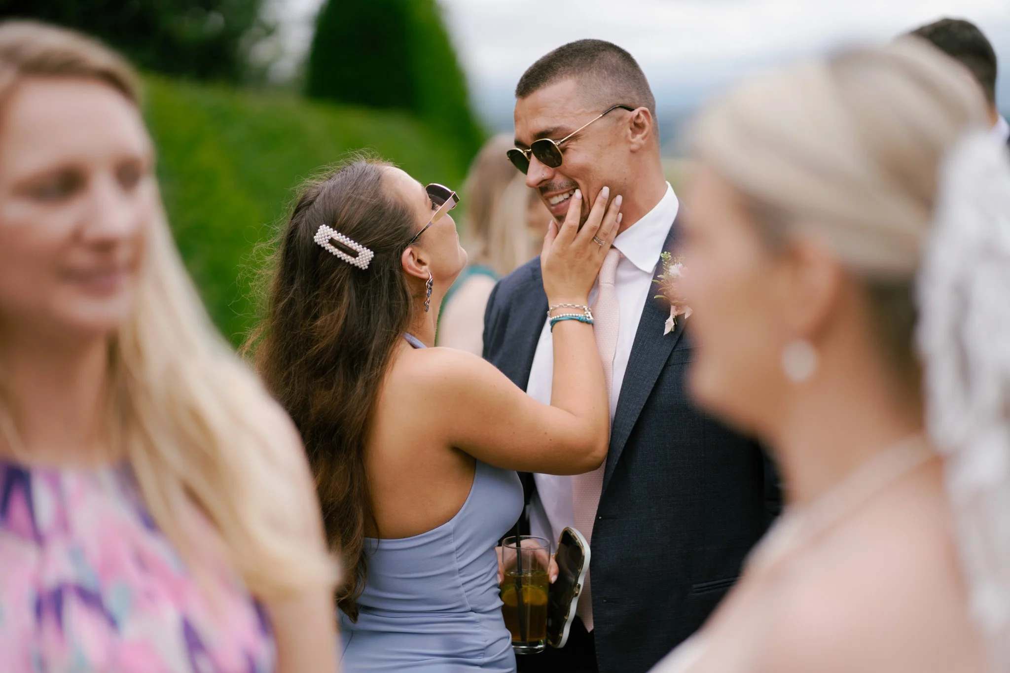 Intimate moment between wedding guests, a woman touches a man's face.