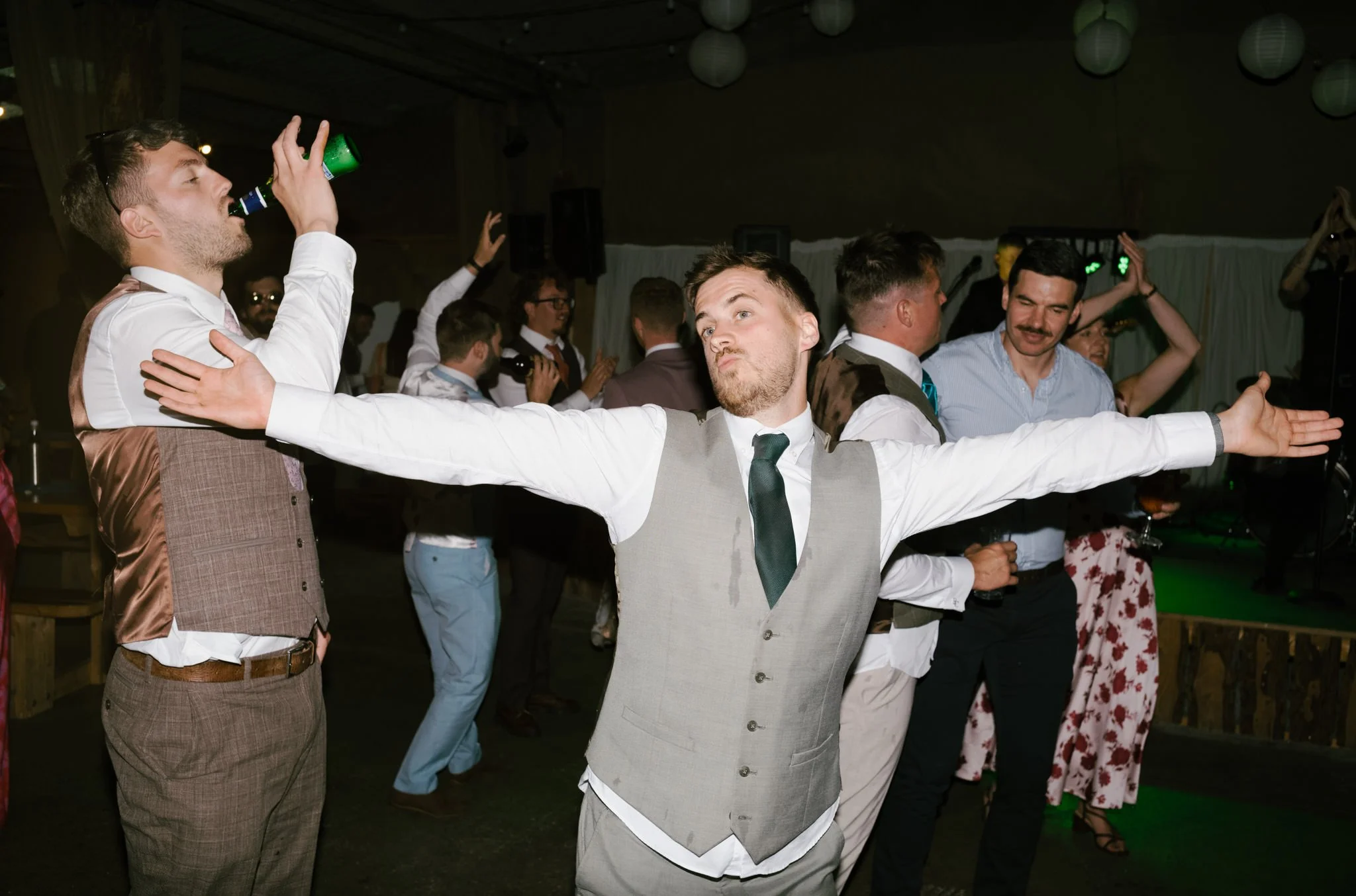 Man spreading his arms wide on the dance floor at a wedding