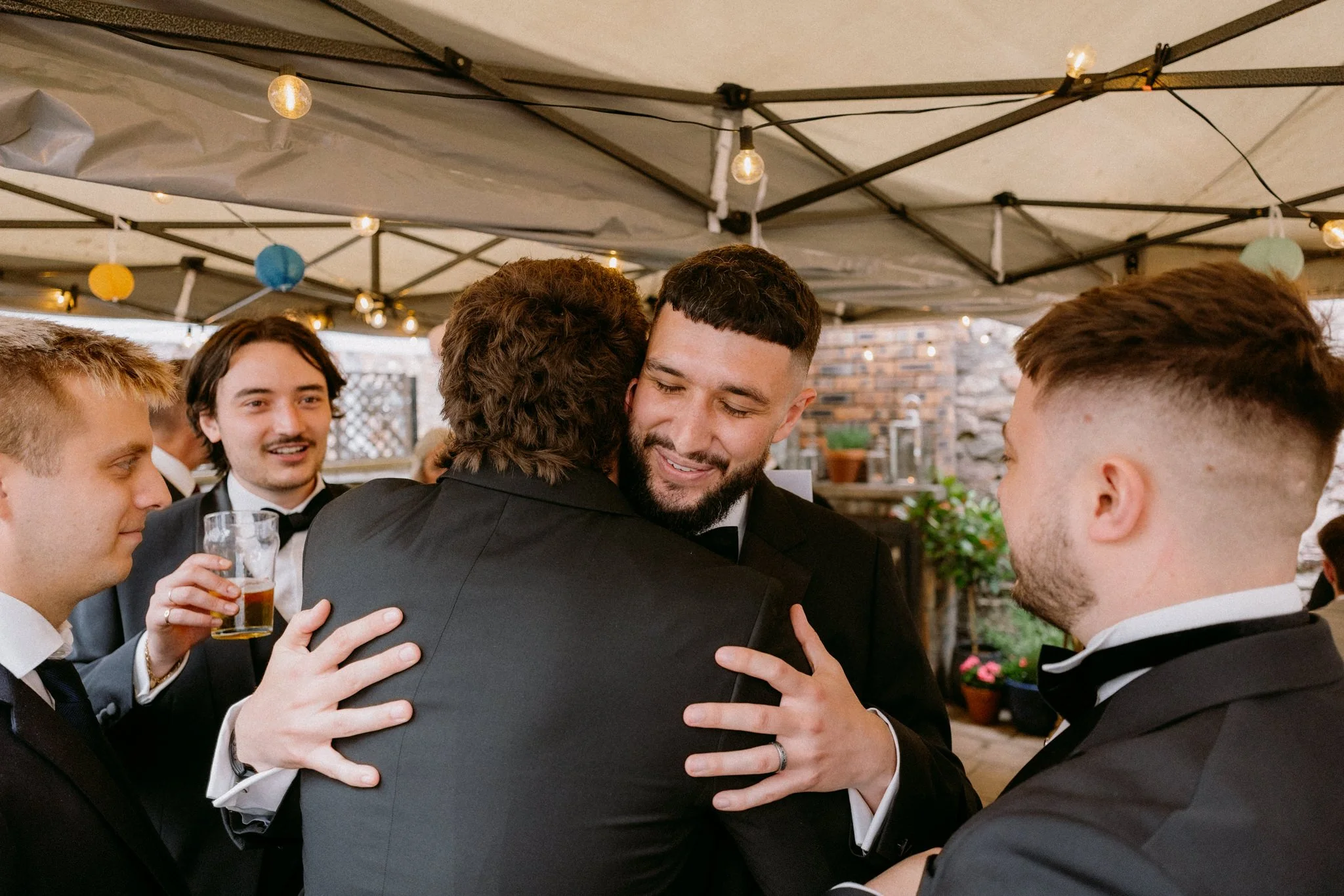 Groom hugs a friend at a wedding at the radnor rooms in bristol