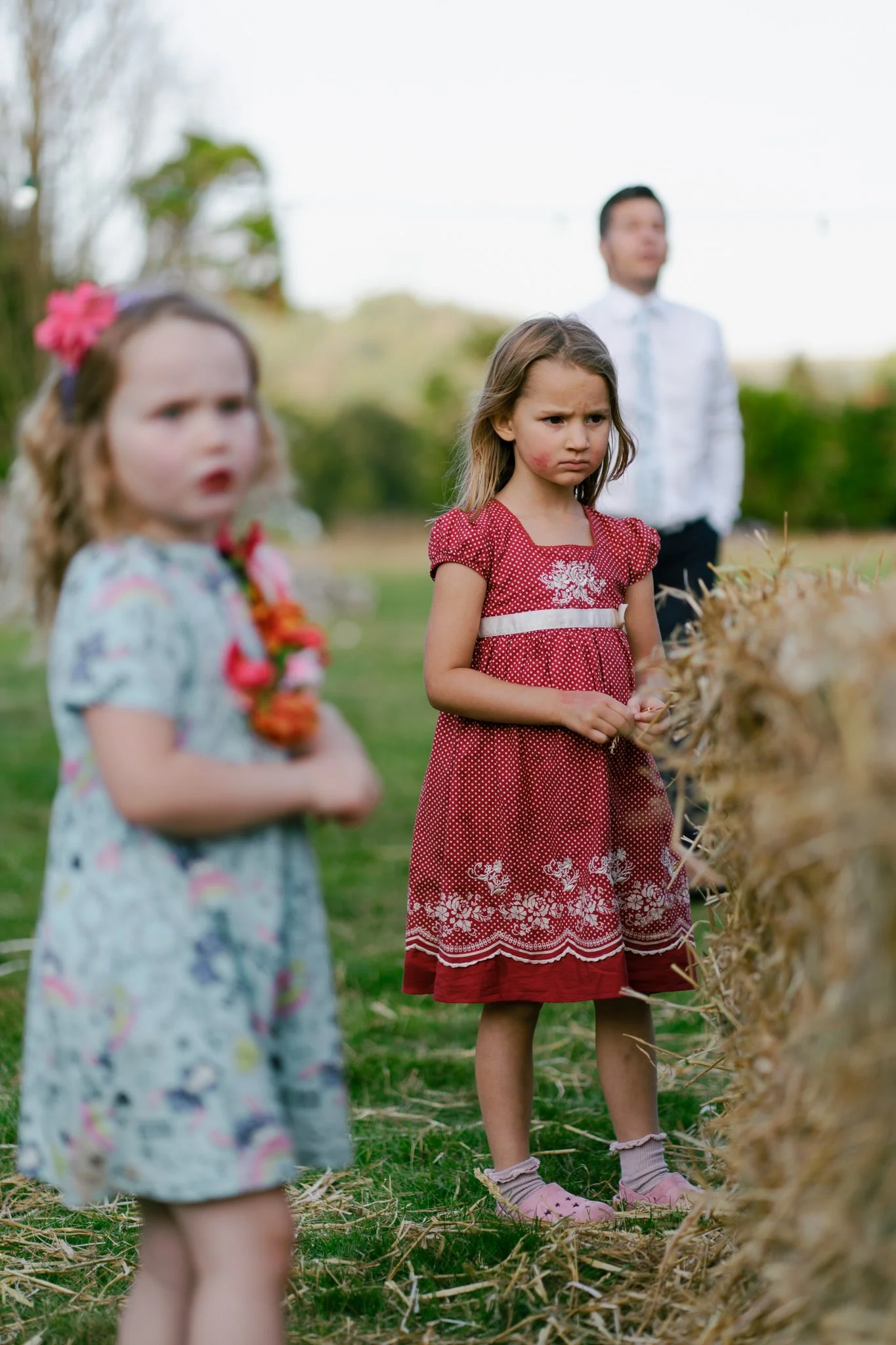 Two young girls at a wedding, one with a red kiss mark on her cheek, the other with red lipstick
