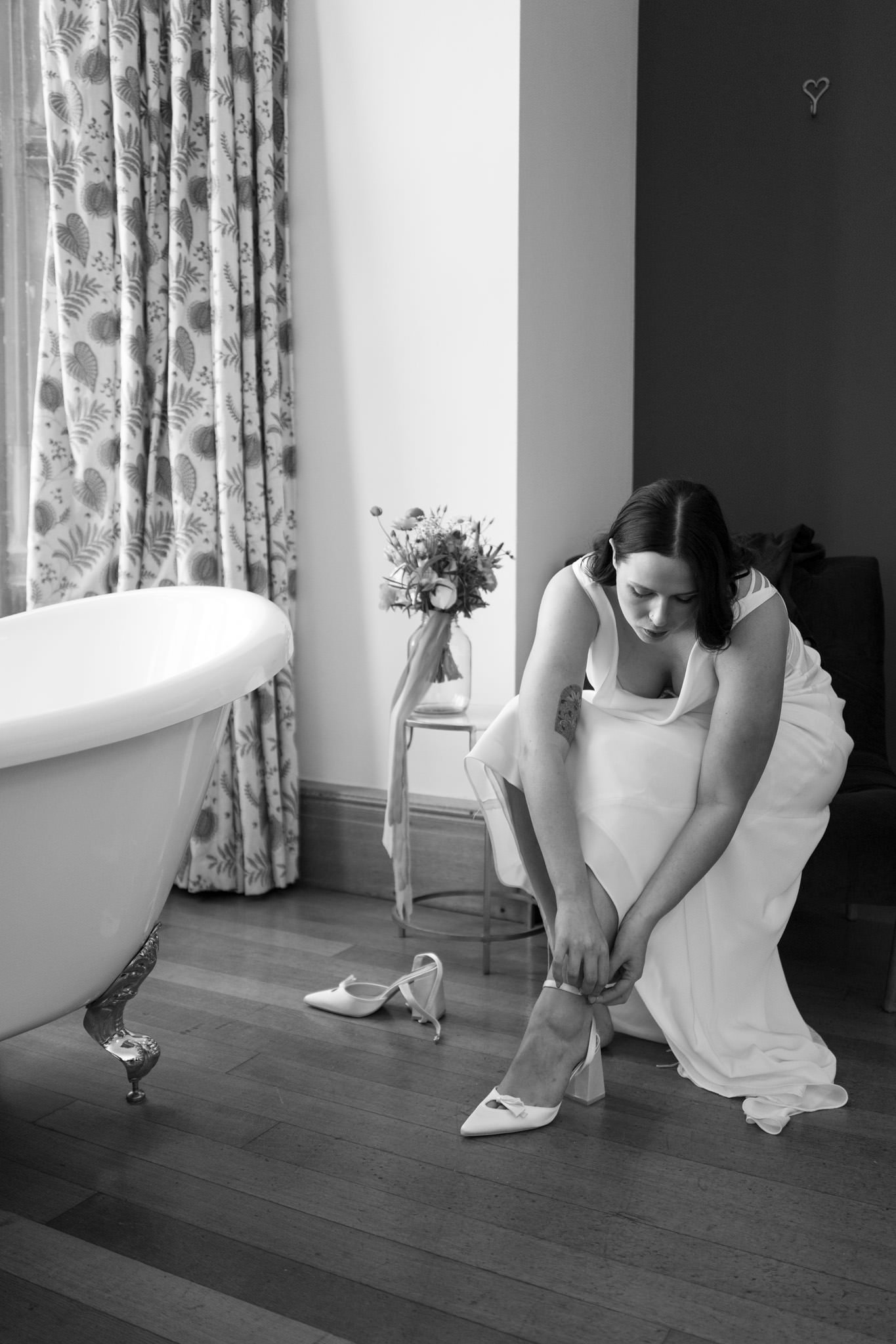 Bride putting shoes on at Coombe Lodge near bristol in black and white