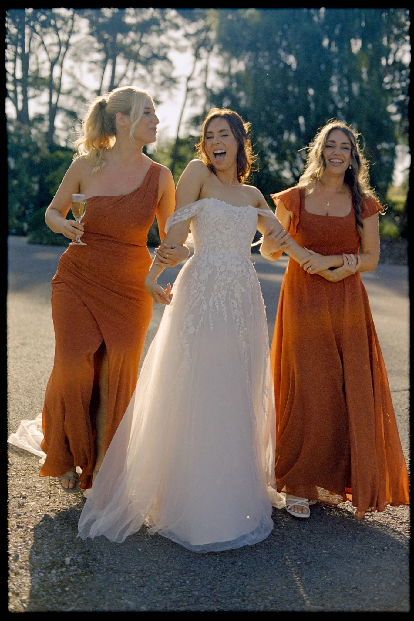 Bride and bridesmaids walk and laugh at Kingscote Barn on Kodak portra 400 film at sunset