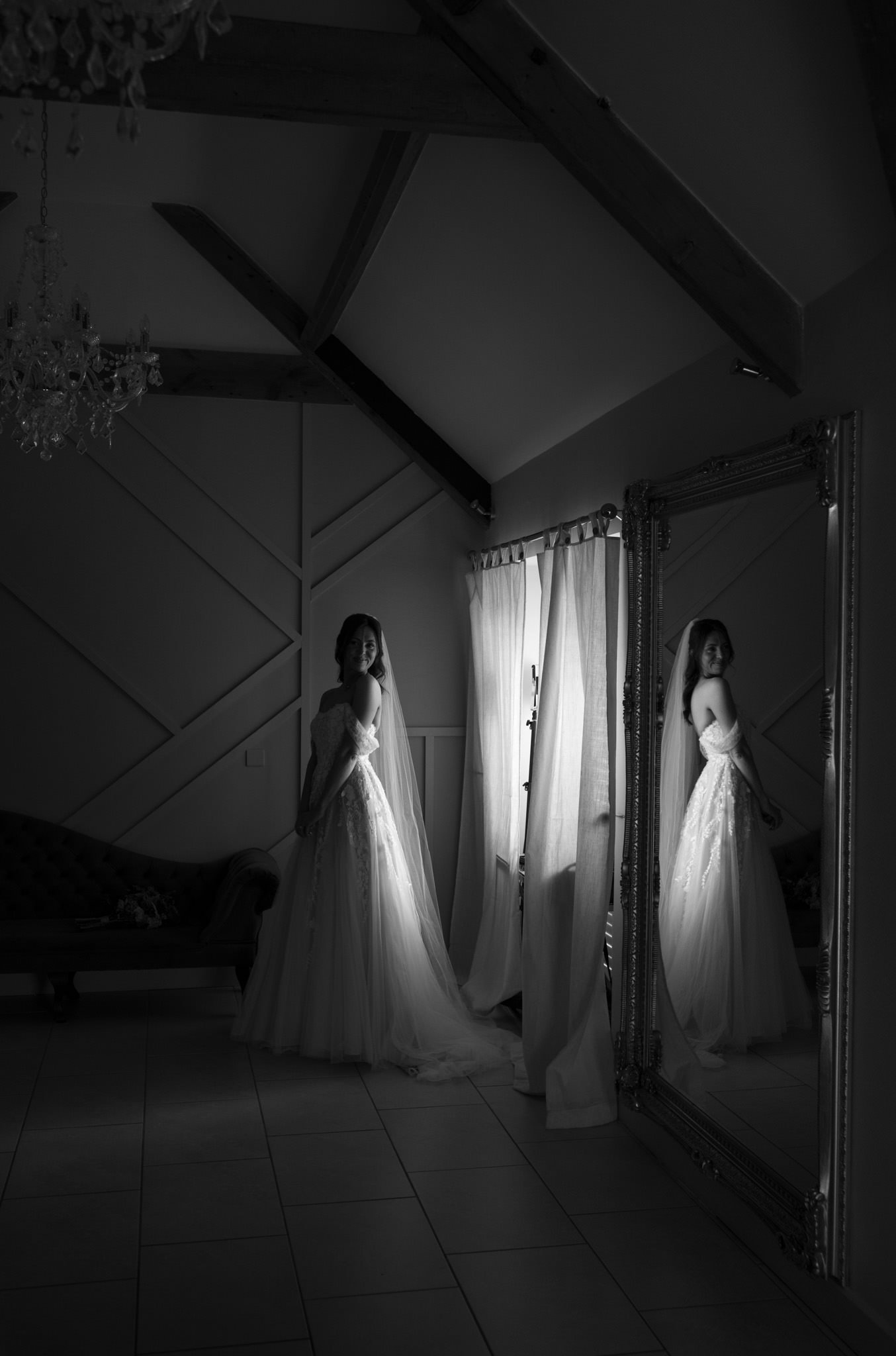 wedding photography of a bride in black and white by a window at Kingscote Barn