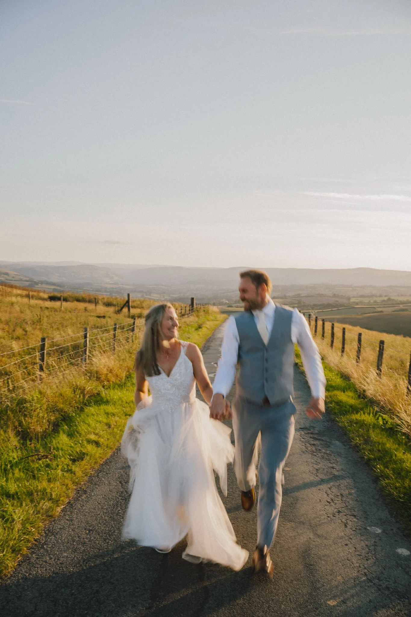 wedding photography of bride and groom walking toward the camera on top of a hill