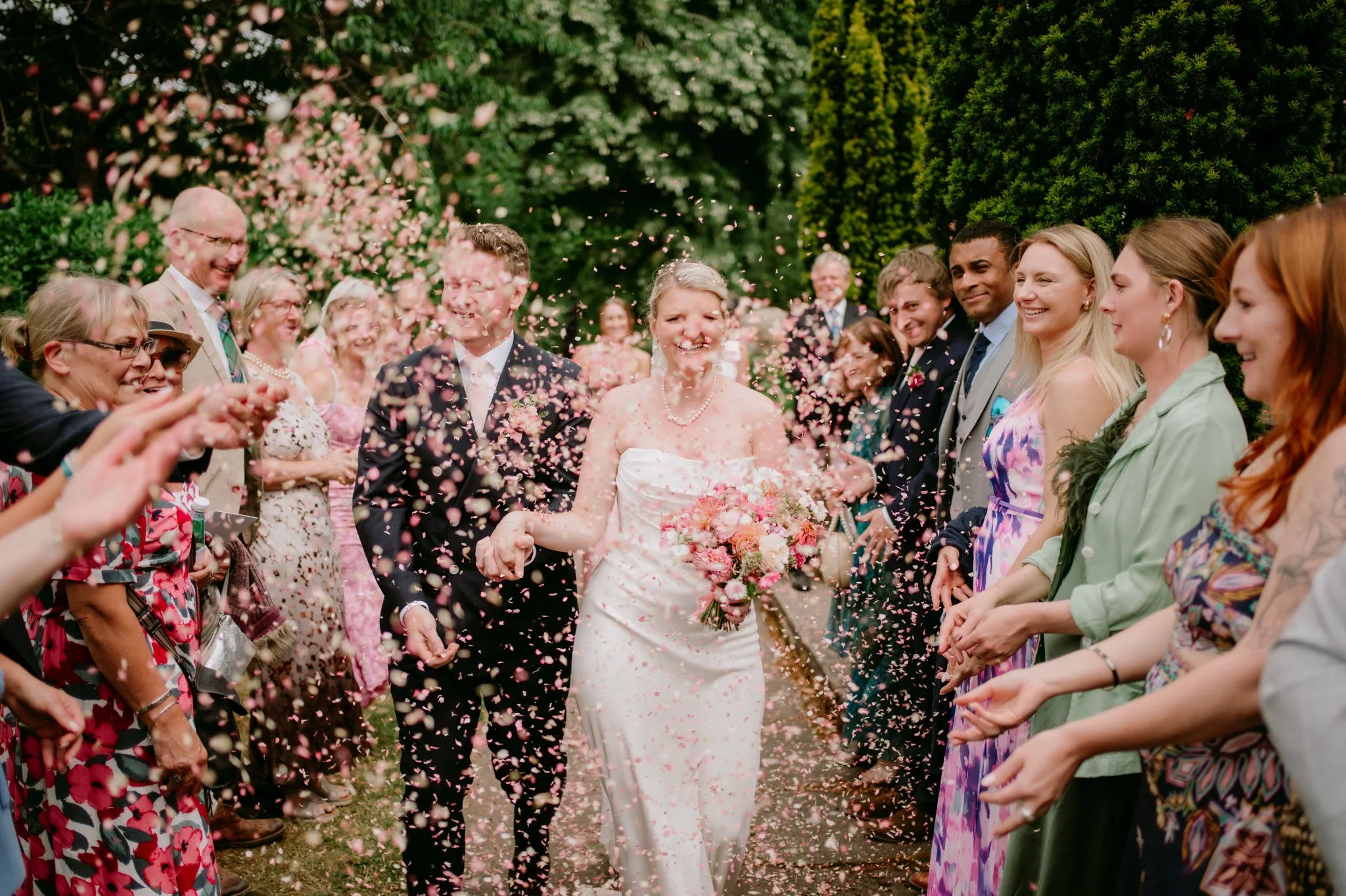 Bride and groom walking through a shower of confetti at Dewsall Court