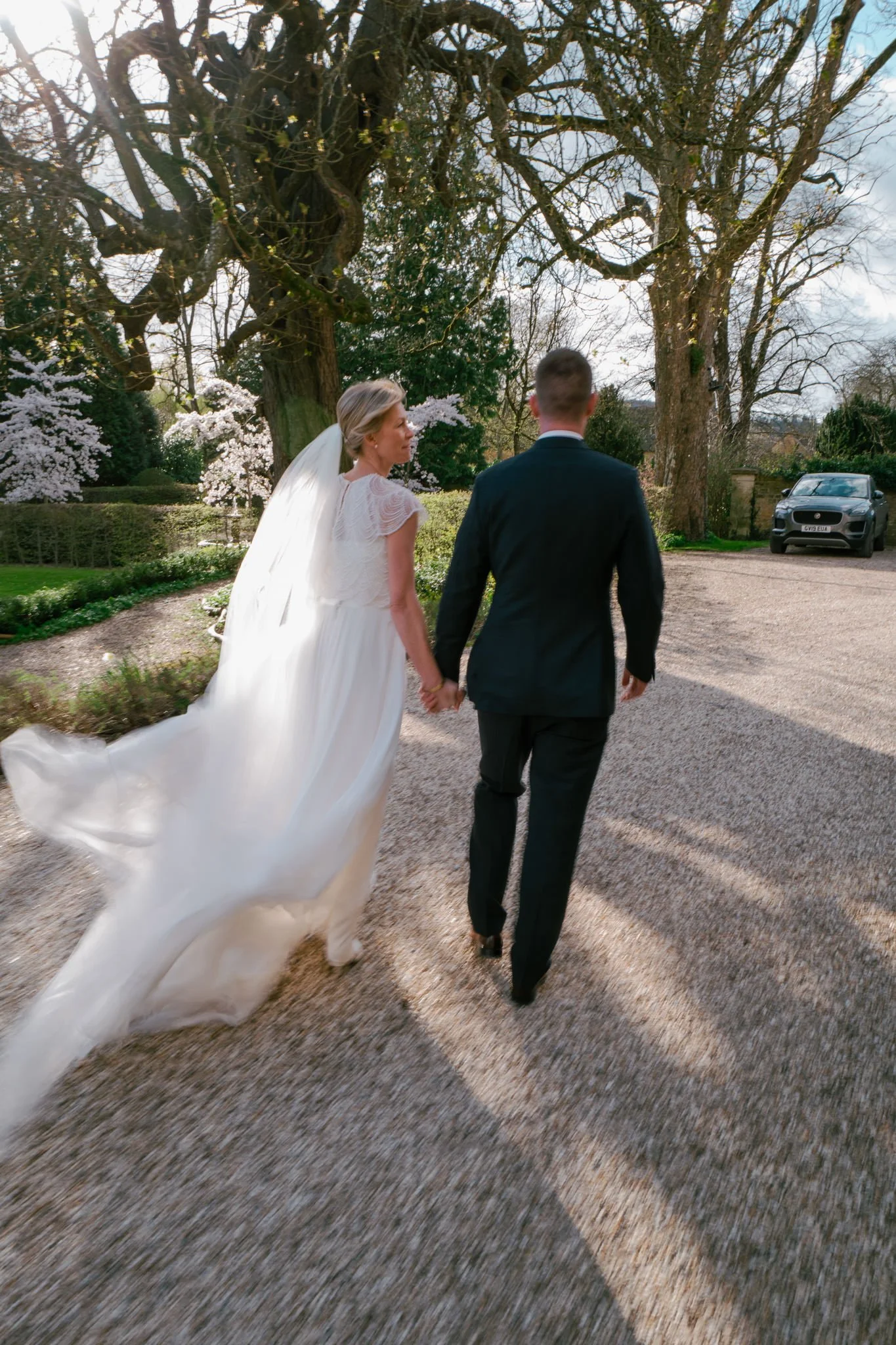 Slow shutter bride and groom walking away from The Slaughters Manor House at a wedding
