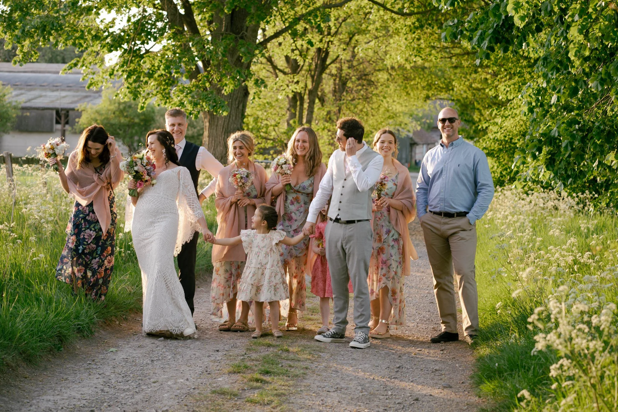Bridal party at sunset walking down a lane and laughing at Bowerchalke Barn in Wiltshire