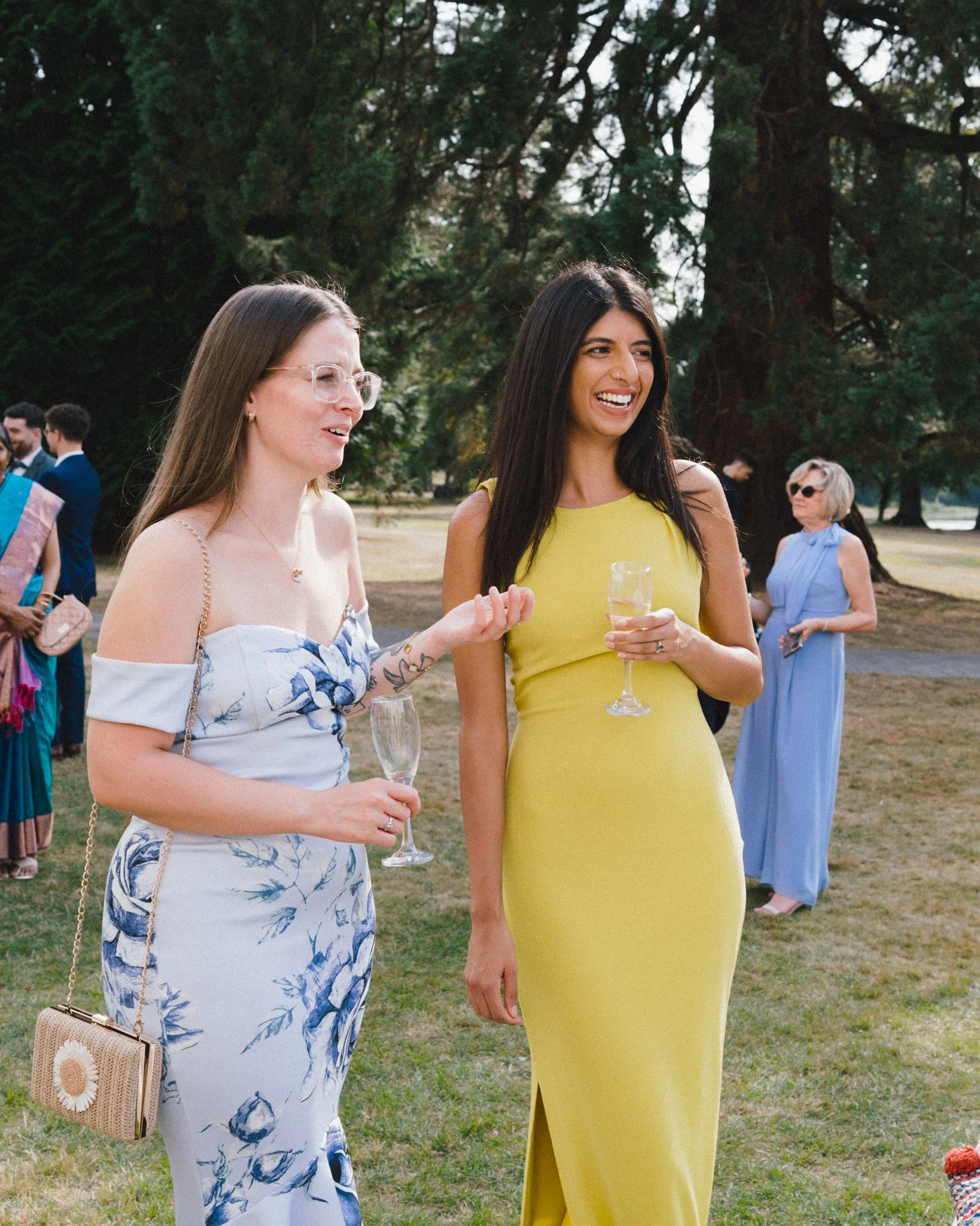 wedding photography of of two female guests, one is of eastern origin in a yellow dress and both are having a nice time