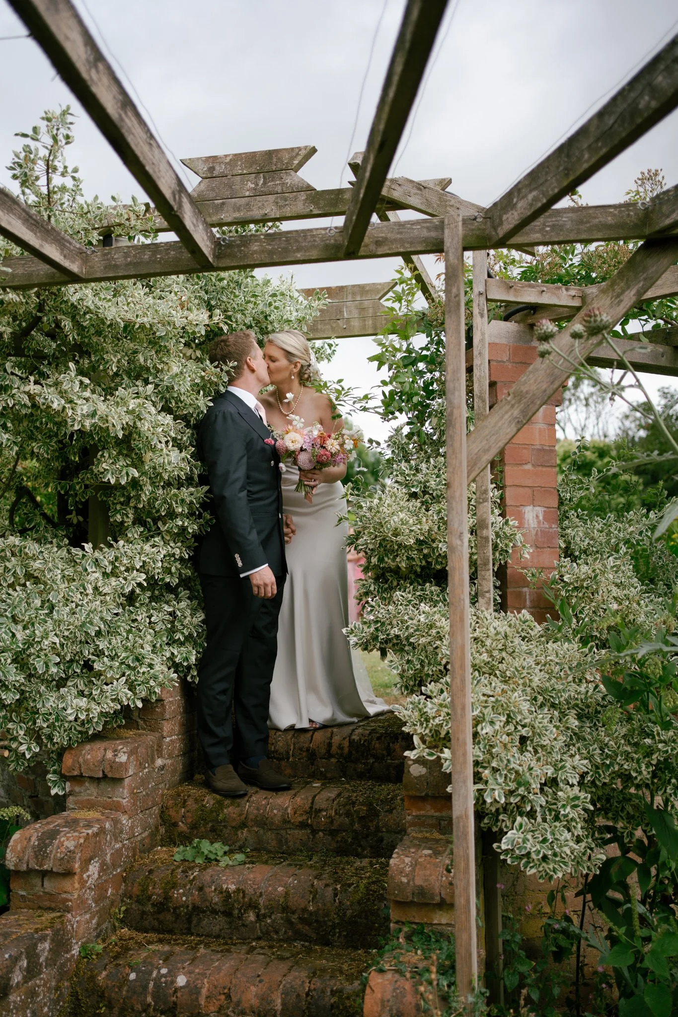 Bride and groom in amongst plants at Dewsall Court