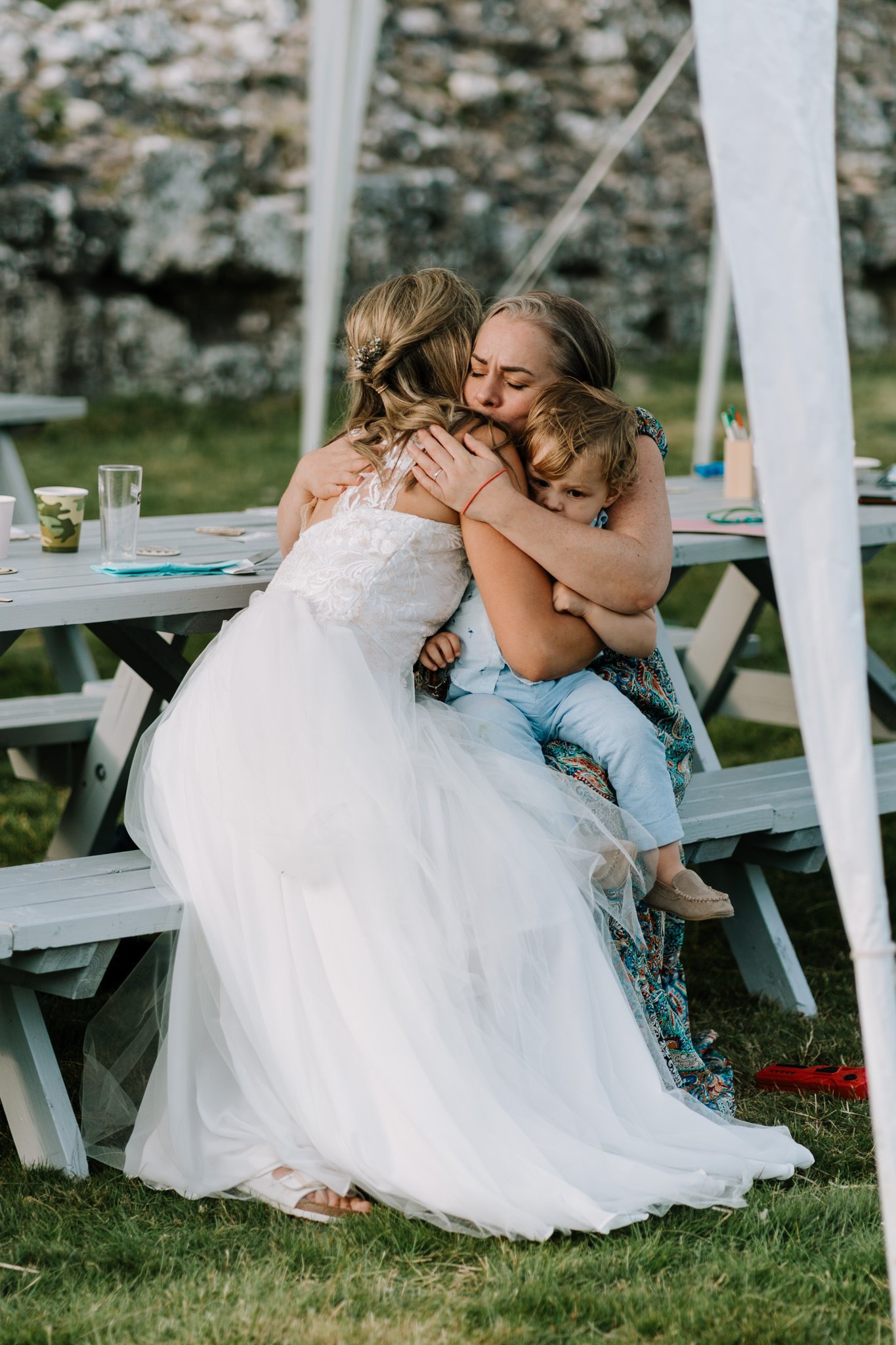 wedding photography of a bride hugging another woman and child in a really beautiful moment