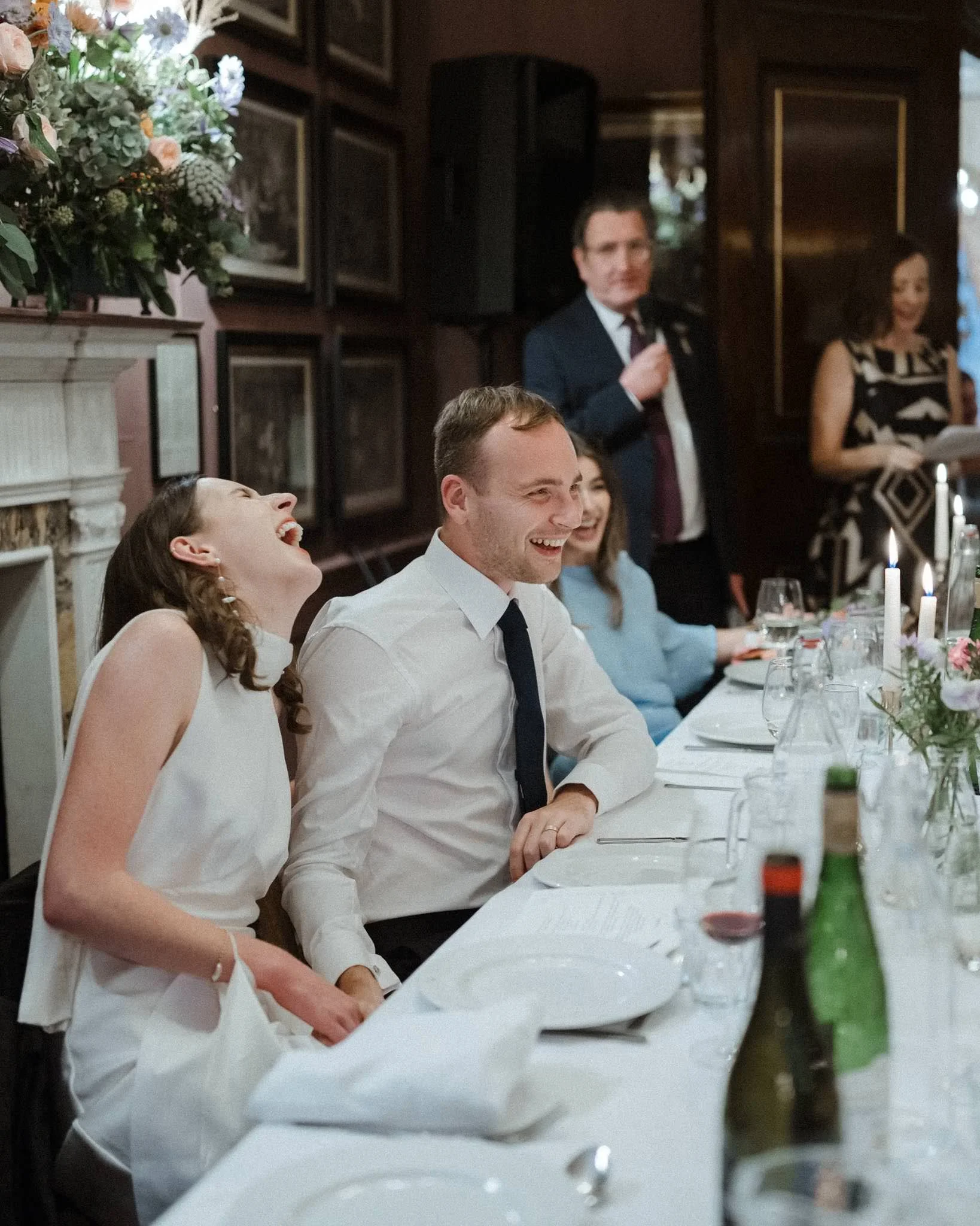 Photograph of bride and groom laughing during speeches at their wedding in Bristol