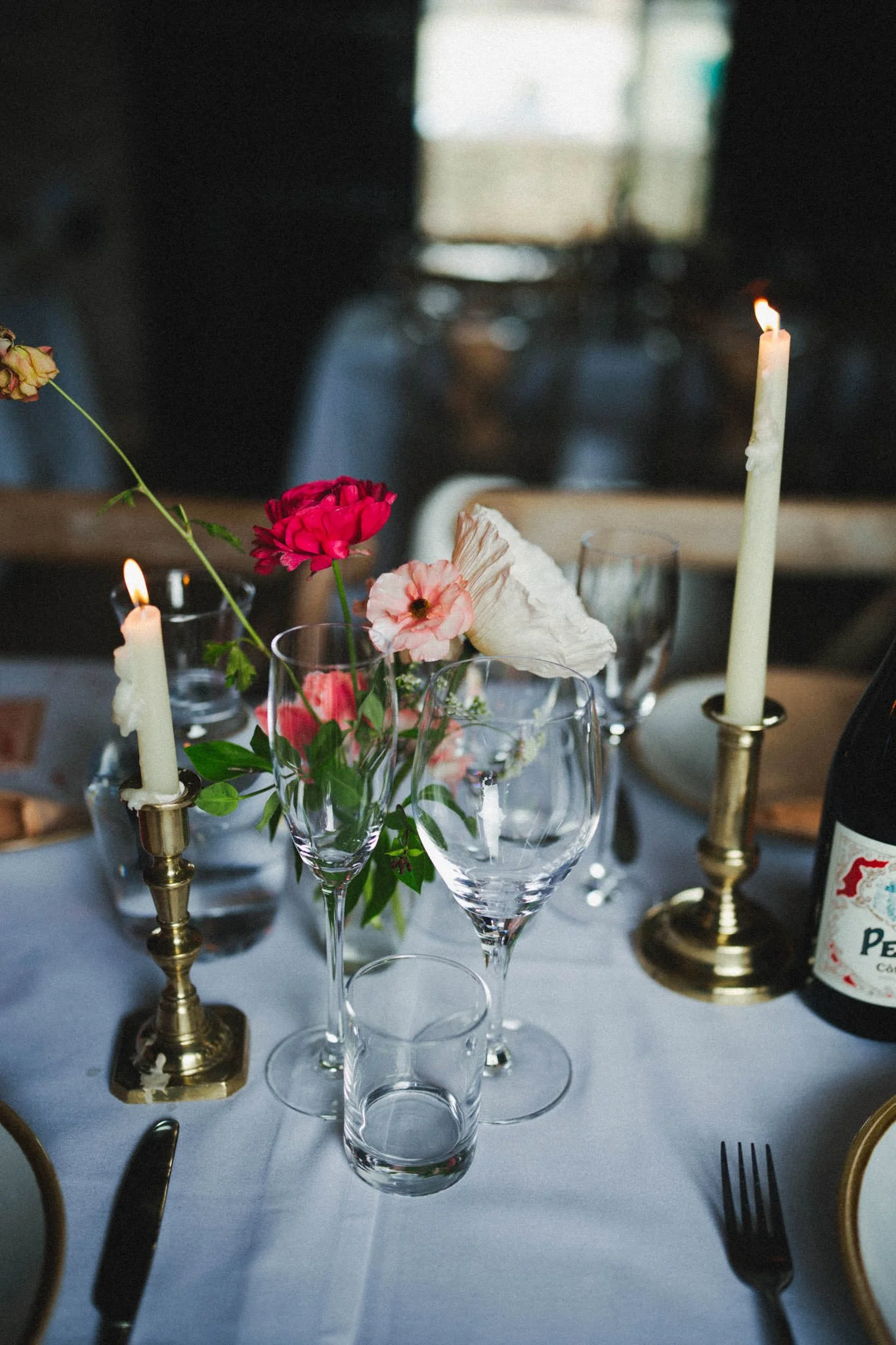 Table details of a candle, glasses and flowers that look a bit like a still life at a Somerset wedding