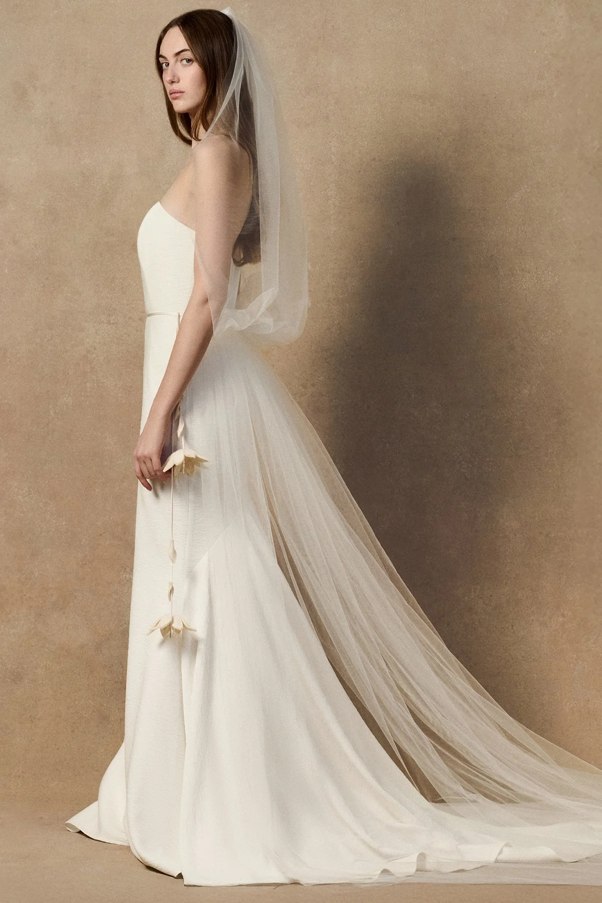 side image of white wedding gown nicole dress in plissé-textured cloqué featuring a curved upward neckline without sleeves. With Phyllis veil